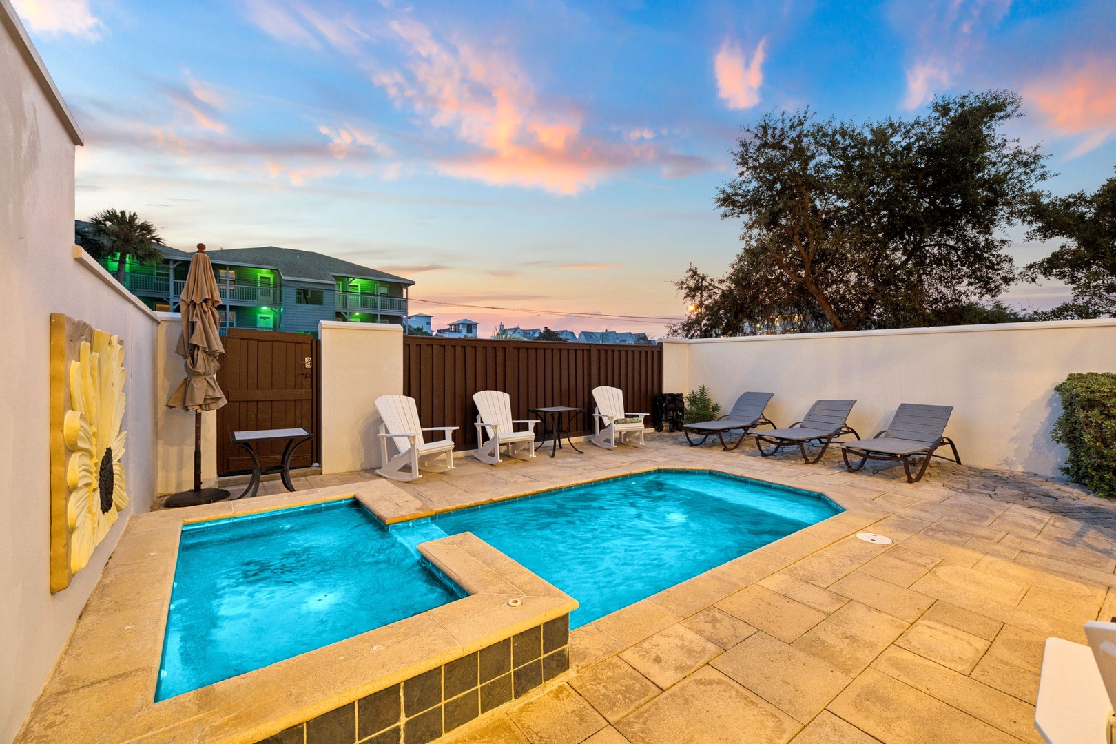 A private pool and hot tub await you under stunning sunset skies, surrounded by comfortable loungers and modern coastal decor—your perfect outdoor retreat for relaxing or entertaining.