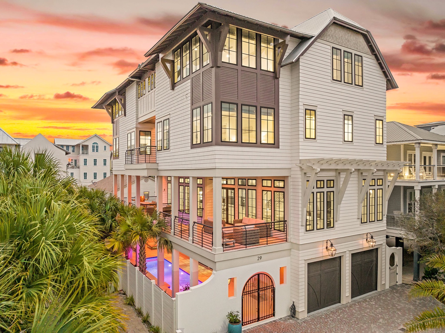 Modern coastal vacation home features bright interiors and tropical landscaping, nestled in an upscale beachside neighborhood during golden hour.