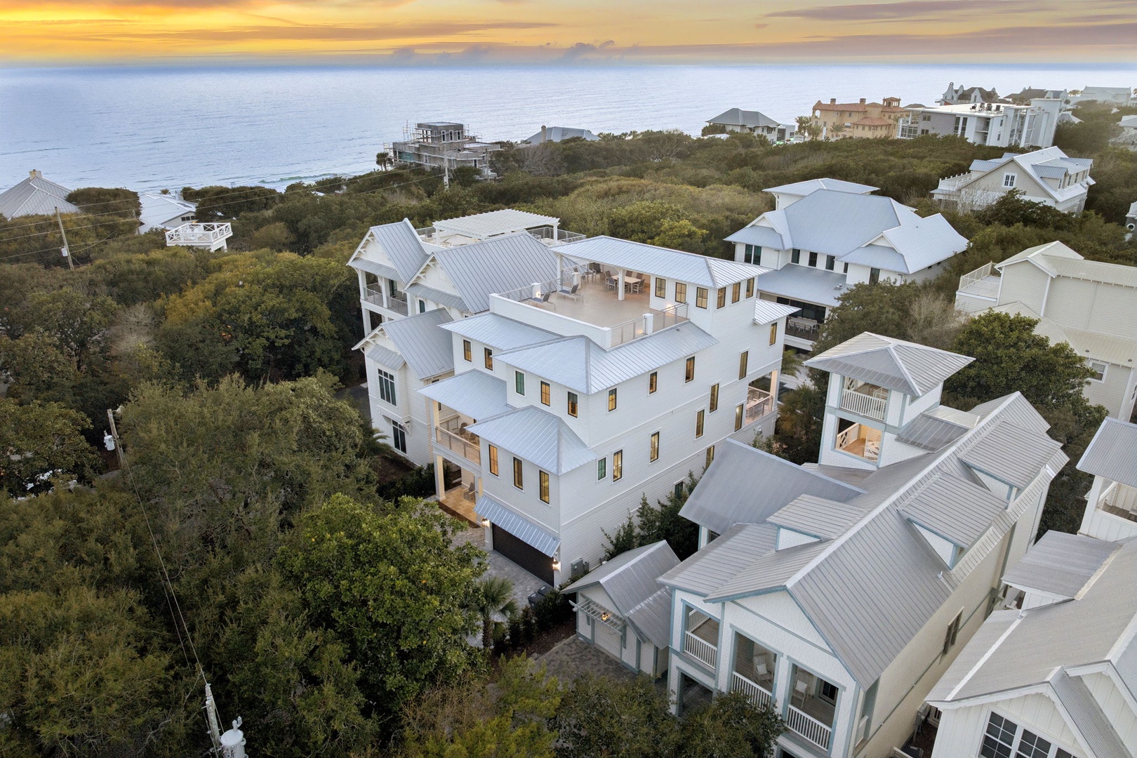 Aerial view of coastal properties nestled among lush vegetation with the Gulf waters visible in the distance during golden hour.