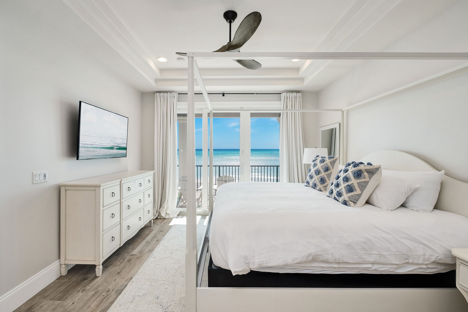 Wake up to stunning ocean views from your private balcony in this serene bedroom retreat with coastal charm and modern comfort.