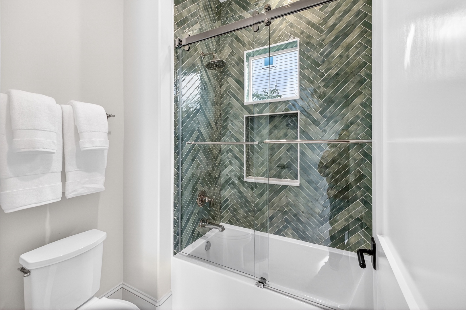 Unwind in your spa-like bathroom featuring stunning herringbone tile, a luxurious soaking tub, and plush white towels waiting for you.