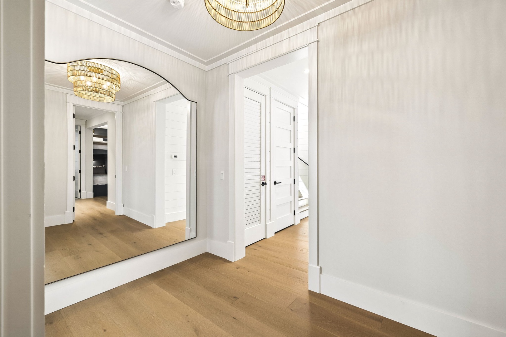 Step into this bright, airy hallway where elegant lighting and warm wood floors guide you through the space. The thoughtful design creates a welcoming first impression that sets the tone for your entire stay.
