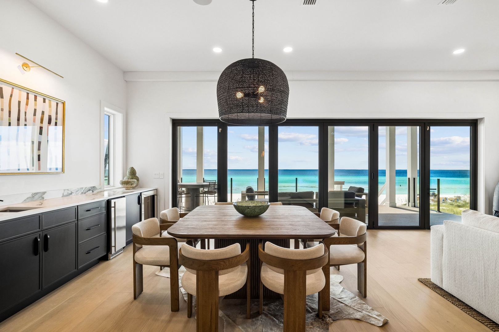 Gather around the table and soak in those stunning ocean views through floor-to-ceiling windows. Imagine sharing meals here, with turquoise waters and white sand right outside your door—your own coastal retreat.