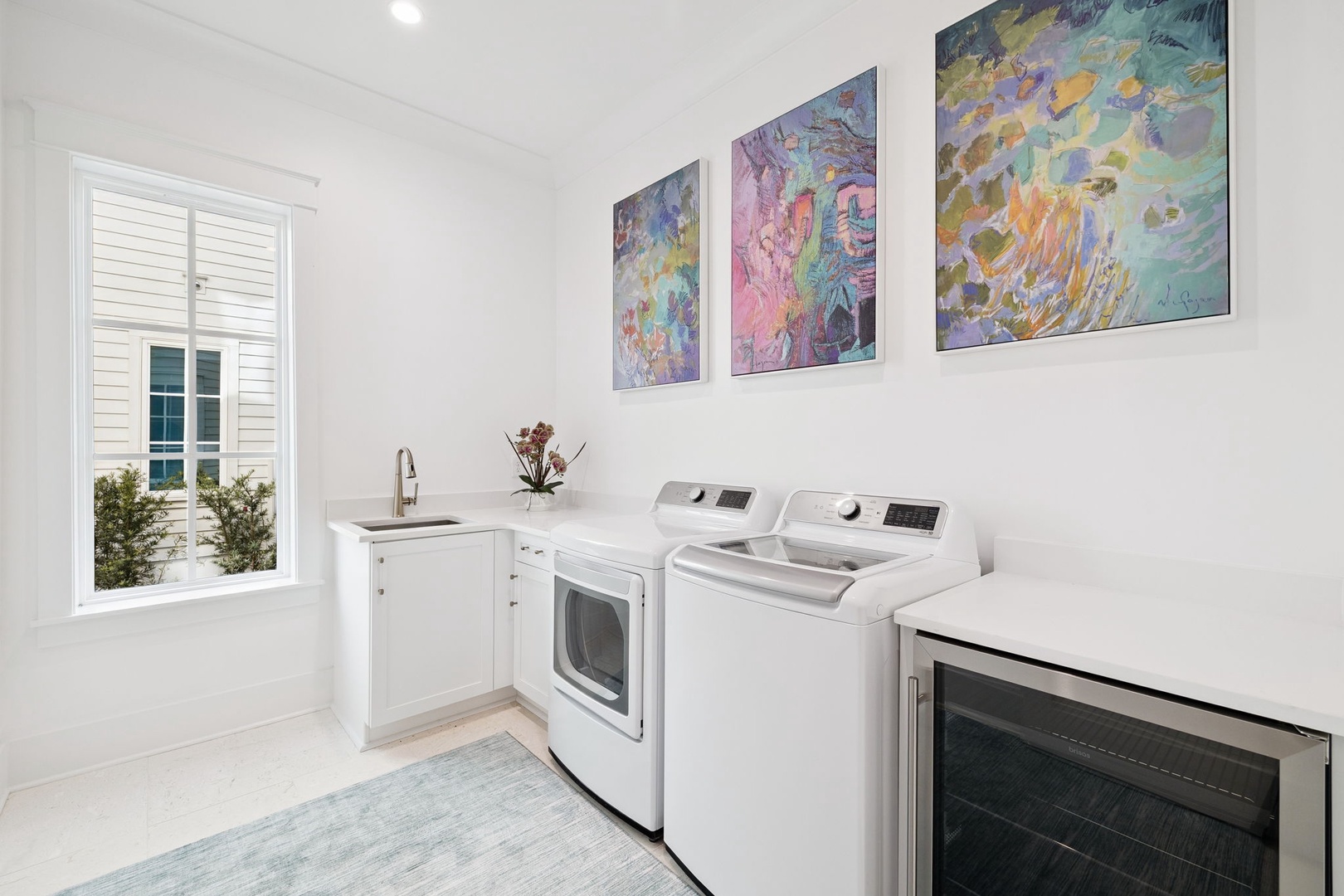 Your bright, well-designed laundry room makes washing effortless with colorful artwork brightening your daily routines.