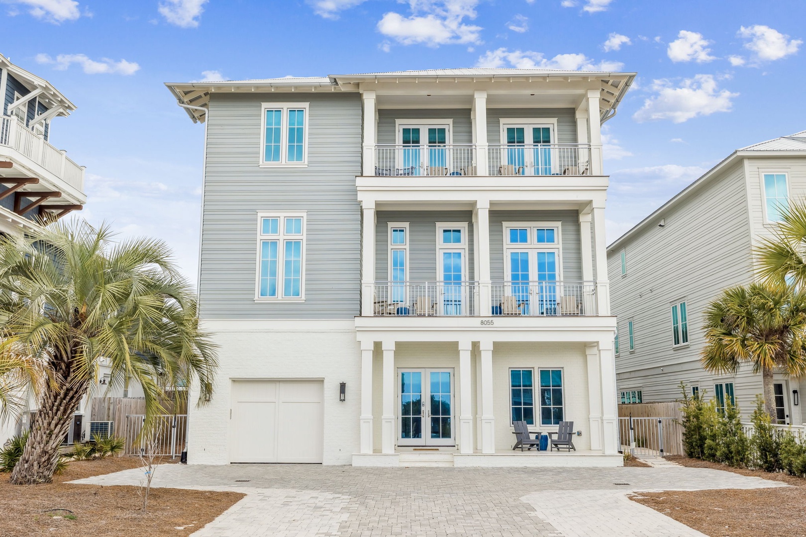 Elegant three-story coastal home with spacious balconies and tropical landscaping in a peaceful residential setting.