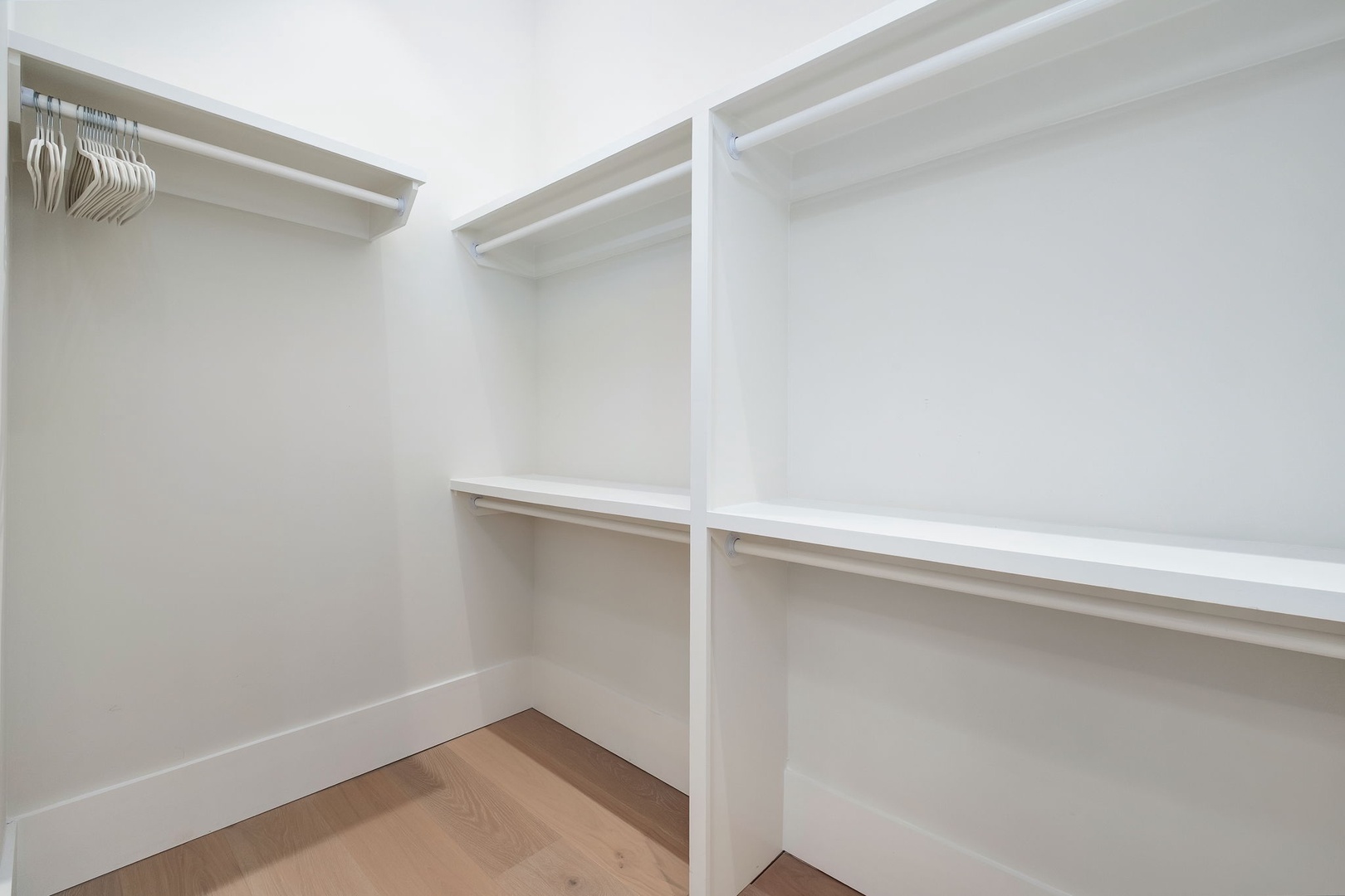 Your walk-in closet offers generous storage with multiple hanging rods and spacious shelving, ready for your wardrobe.