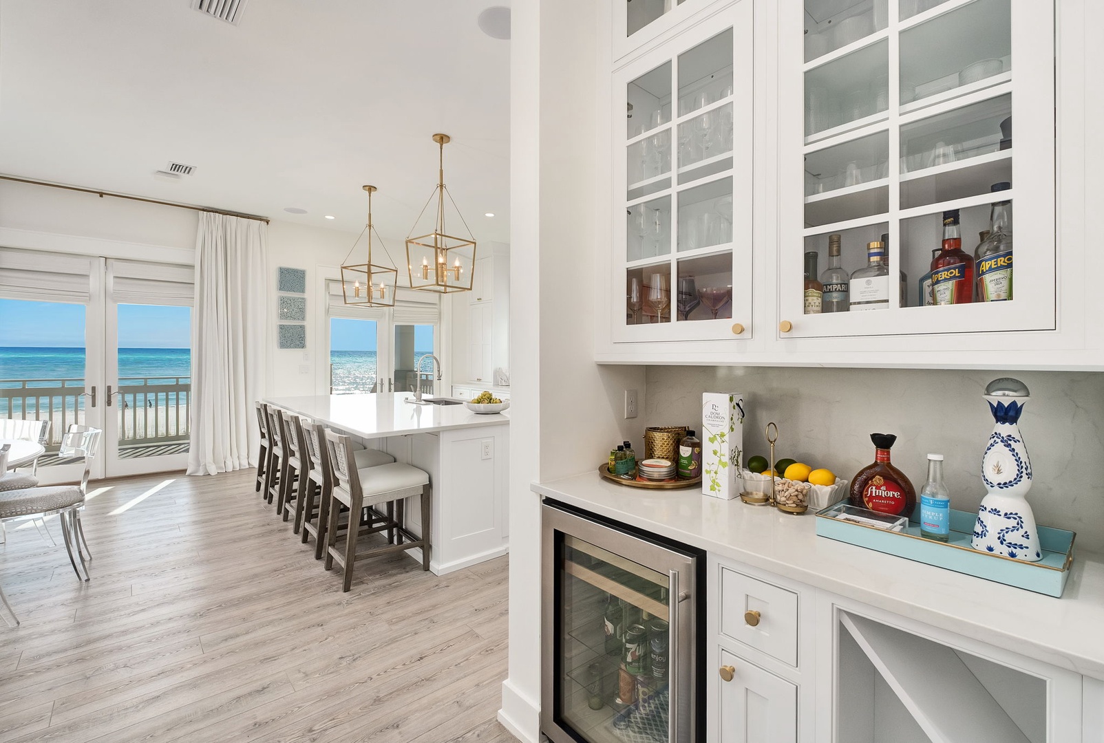 Gather around your bright coastal kitchen where ocean breezes and turquoise waves fill every view, making meal prep feel like a beachside celebration.