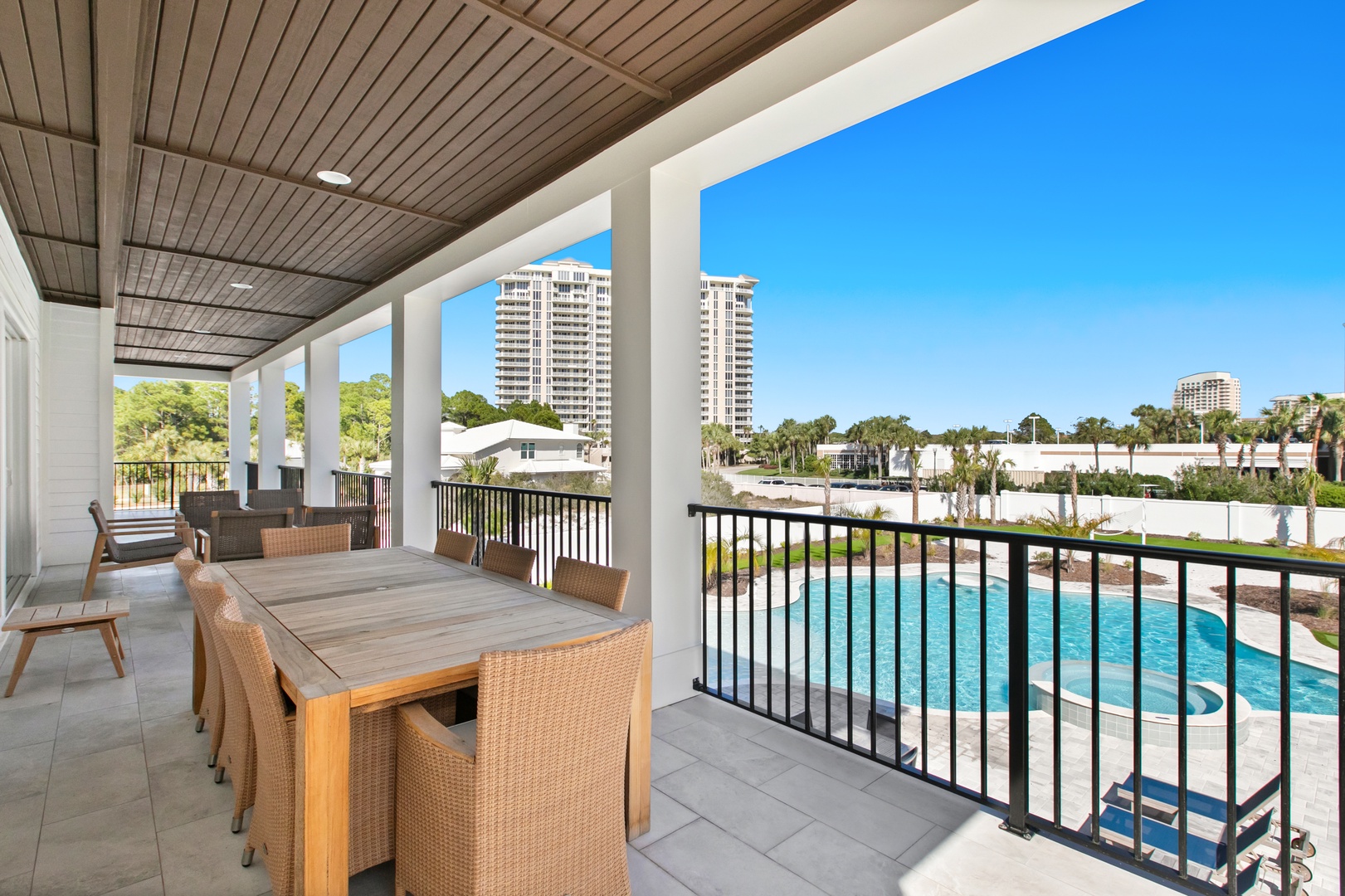 A spacious covered terrace where you can gather for meals with stunning pool and community views stretching out before you under bright blue skies.