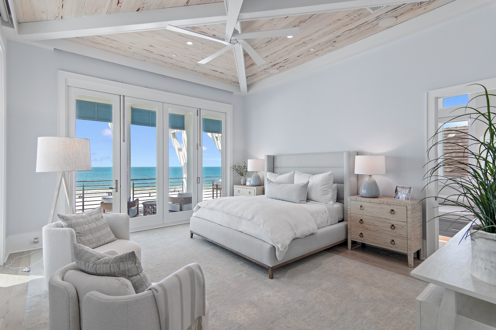 Step into your serene coastal retreat, where vaulted ceilings with natural wood beams soar above plush furnishings and the ocean beckons just beyond your private balcony doors.