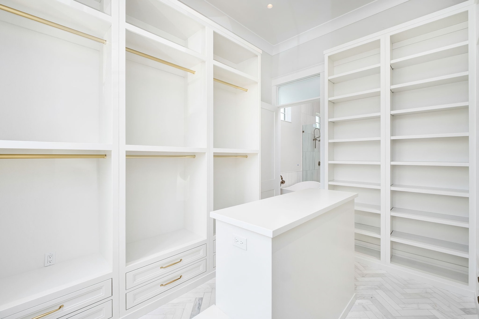 A pristine walk-in closet offering abundant storage with built-in shelving, hanging rods, and elegant drawers with gold accents—your organized, luxurious retreat.