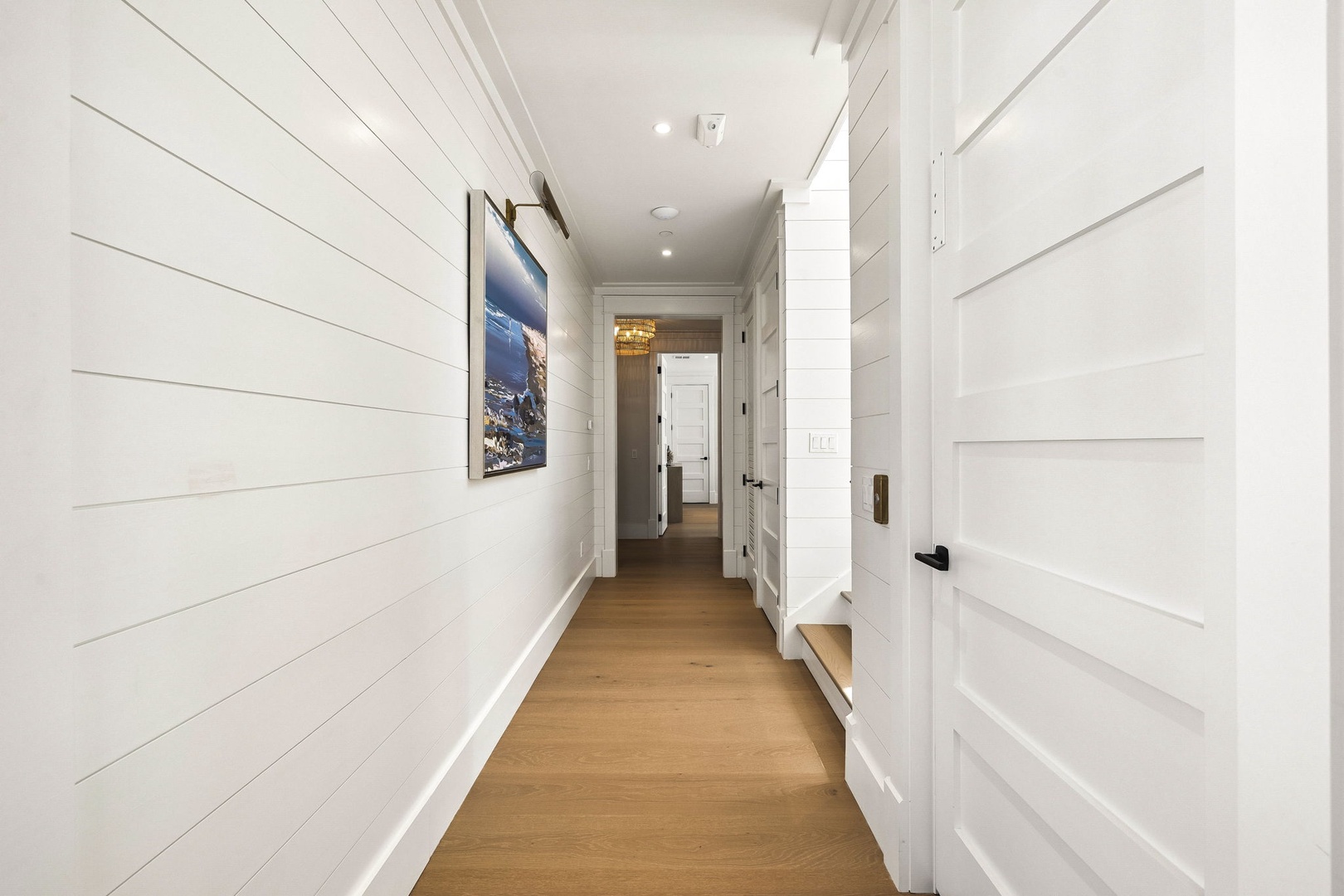 Step into this charming hallway with warm wood floors and coastal-inspired shiplap walls that create a welcoming, serene atmosphere throughout your home.