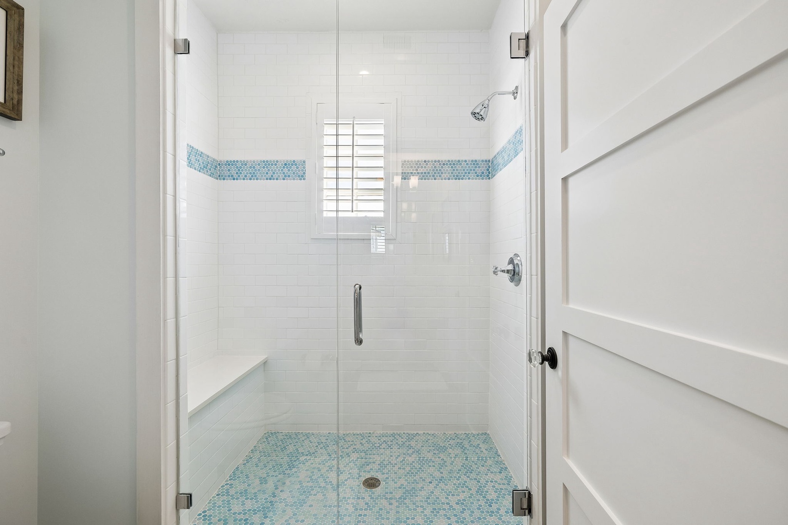 Spa-inspired shower with turquoise mosaic accents and glass enclosure creates a serene coastal sanctuary. Bright white subway tile and spacious design make this the perfect morning retreat.