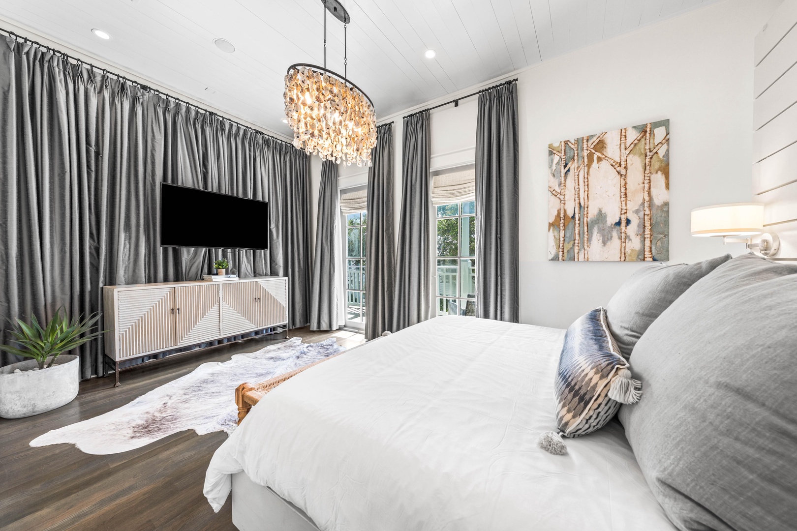 Sink into luxury with crisp white linens and a sparkling chandelier overhead. Your private sanctuary awaits with modern elegance.