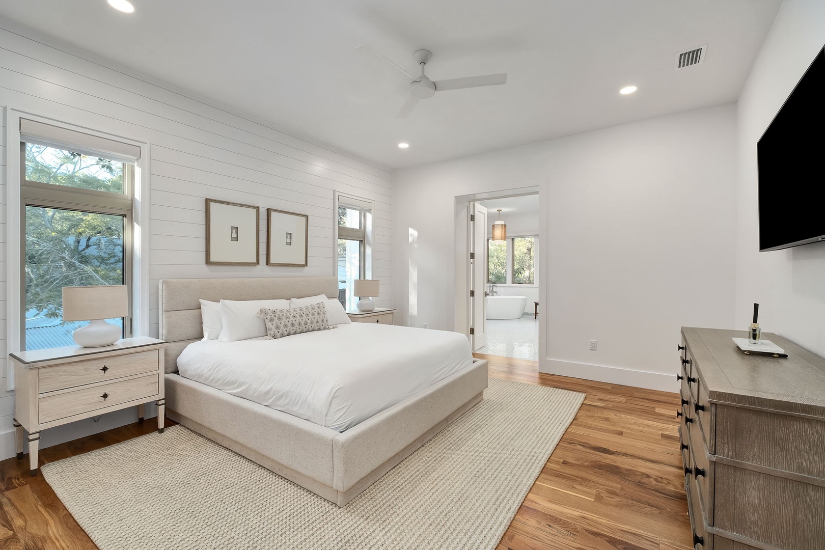 Drift into peaceful sleep in your bright, modern bedroom with plush linens and calming natural light streaming through large windows.