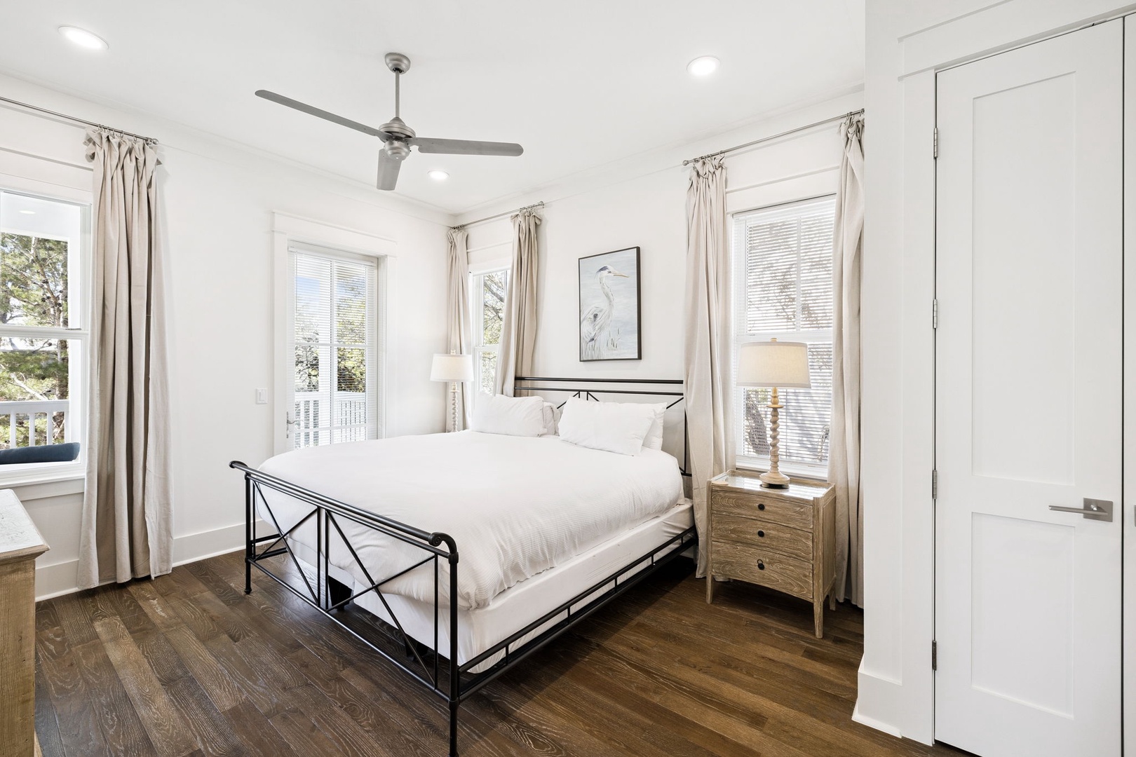 Unwind in your serene bedroom sanctuary with crisp white linens, natural light, and a gentle ceiling fan for perfect comfort.