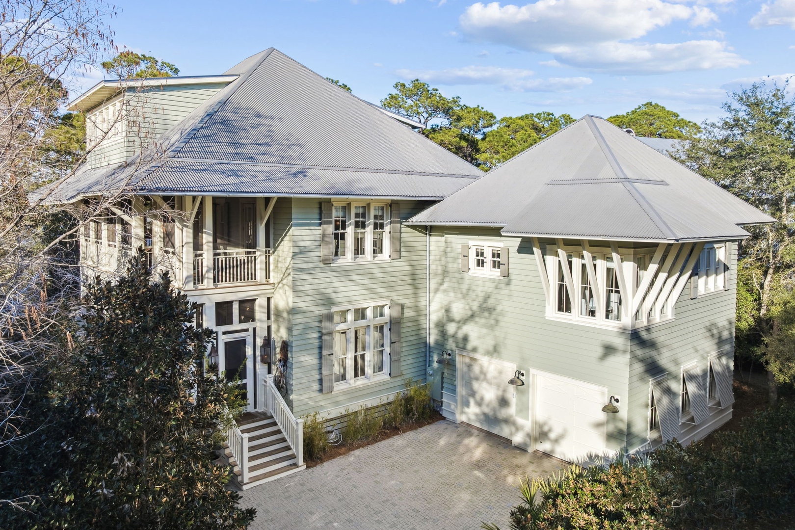 A beautiful coastal-style vacation home nestled among mature trees, featuring classic architecture and peaceful natural surroundings.