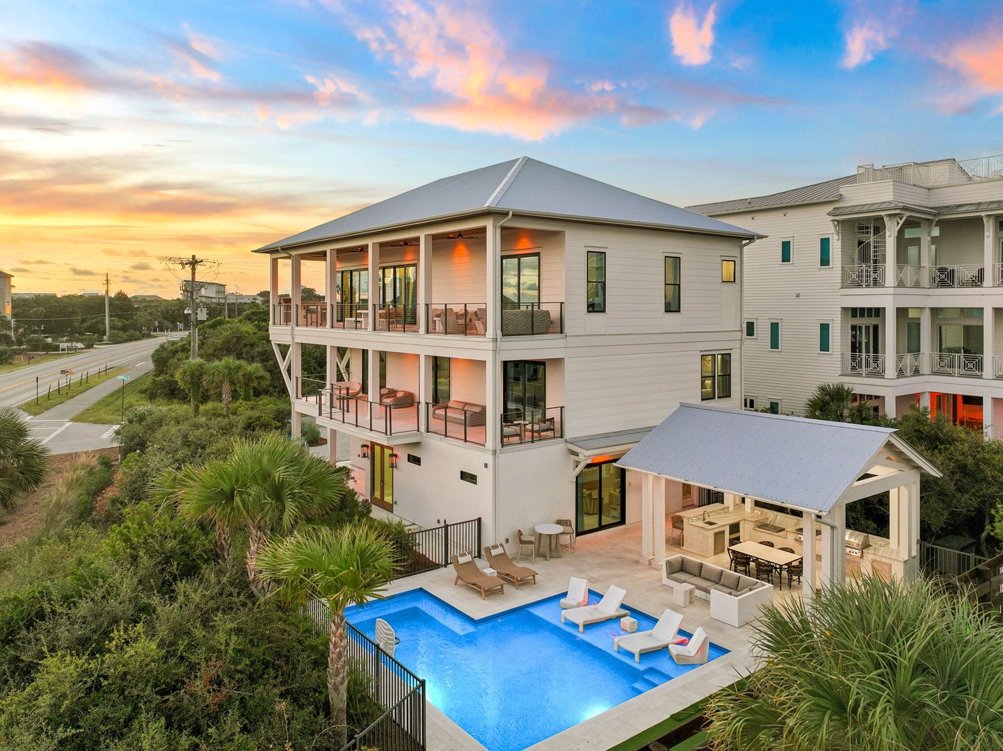 This stunning three-story coastal retreat features a sparkling private pool, spacious covered terraces, and an elegant outdoor pavilion—perfect for relaxing after beach days or gathering with loved ones under painted sunset skies.