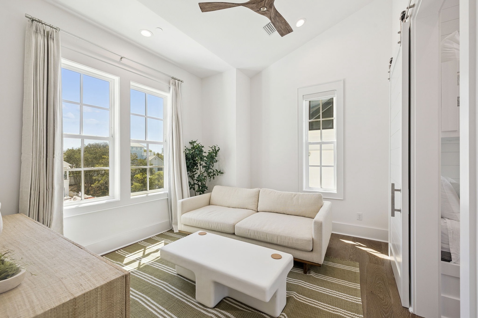 Relax in your bright living space with comfortable seating, natural light streaming through large windows, and peaceful neighborhood views.