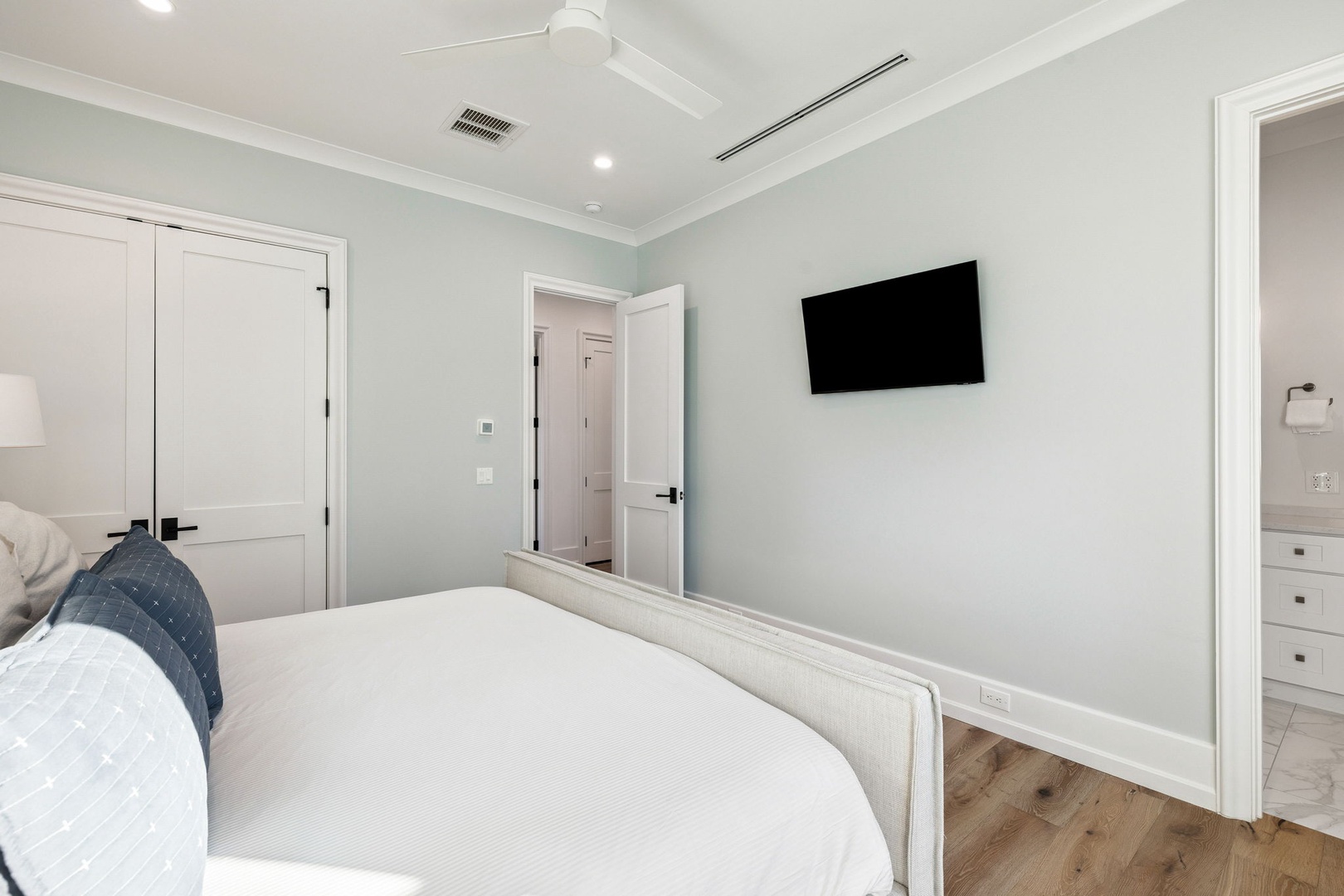 Unwind in your serene bedroom sanctuary with plush bedding and a wall-mounted TV for cozy movie nights.