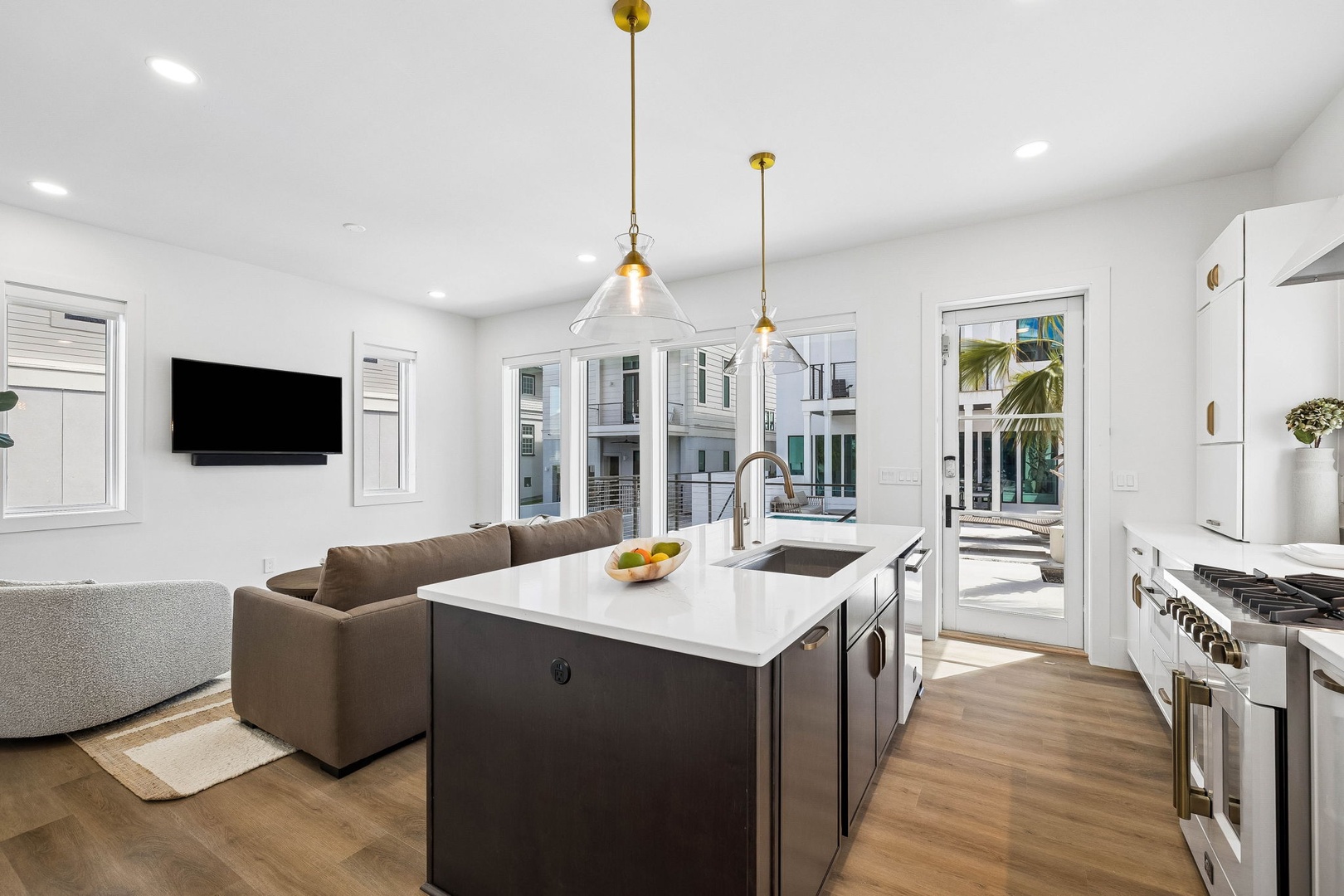 Your open-concept retreat blends modern elegance with coastal ease, where stylish pendant lighting and sleek countertops invite you to cook, gather, and unwind. Glass doors frame your private poolside oasis just steps away.