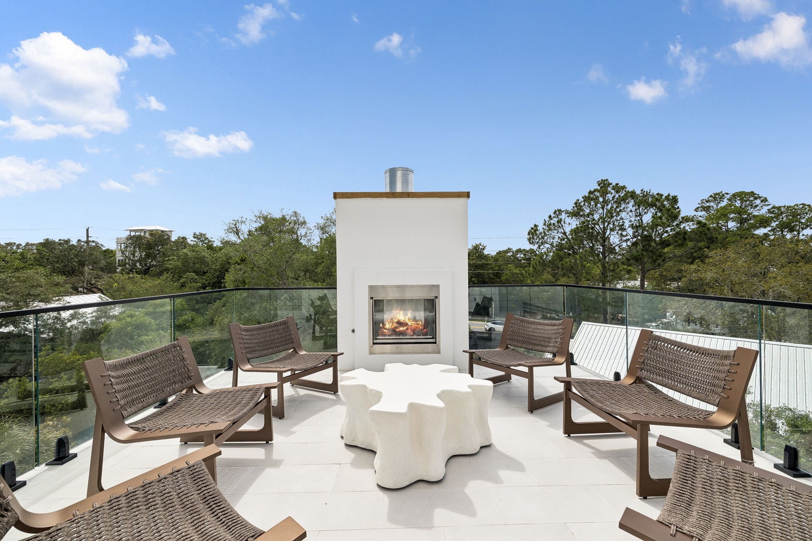 A rooftop terrace with a modern outdoor fireplace and comfortable seating provides a serene spot to enjoy the surrounding treetops and open sky.