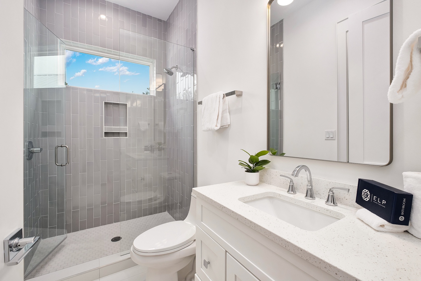 Your private bathroom features elegant gray subway tile and a spacious glass shower with natural light streaming through.