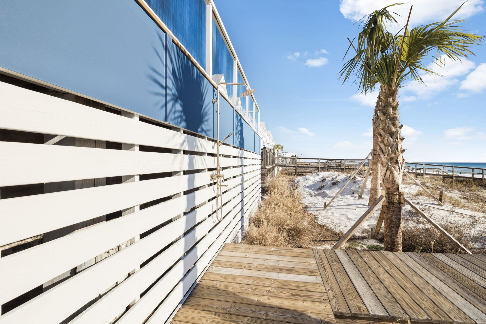 Beachside boardwalk leads to pristine sandy shores with tropical palms and endless ocean views.