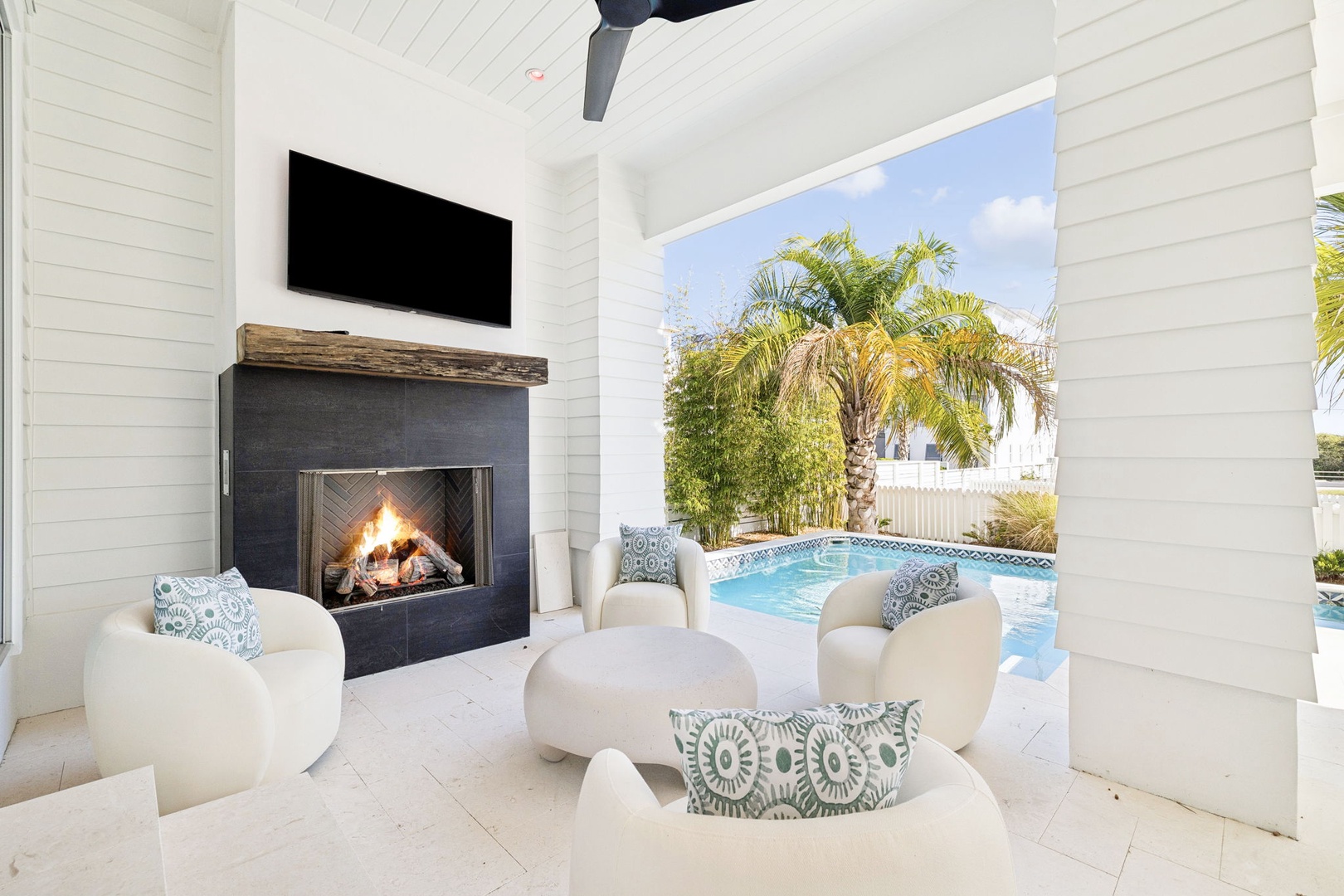 Cozy up in your private outdoor living room with fireplace while enjoying direct pool access and tropical views.