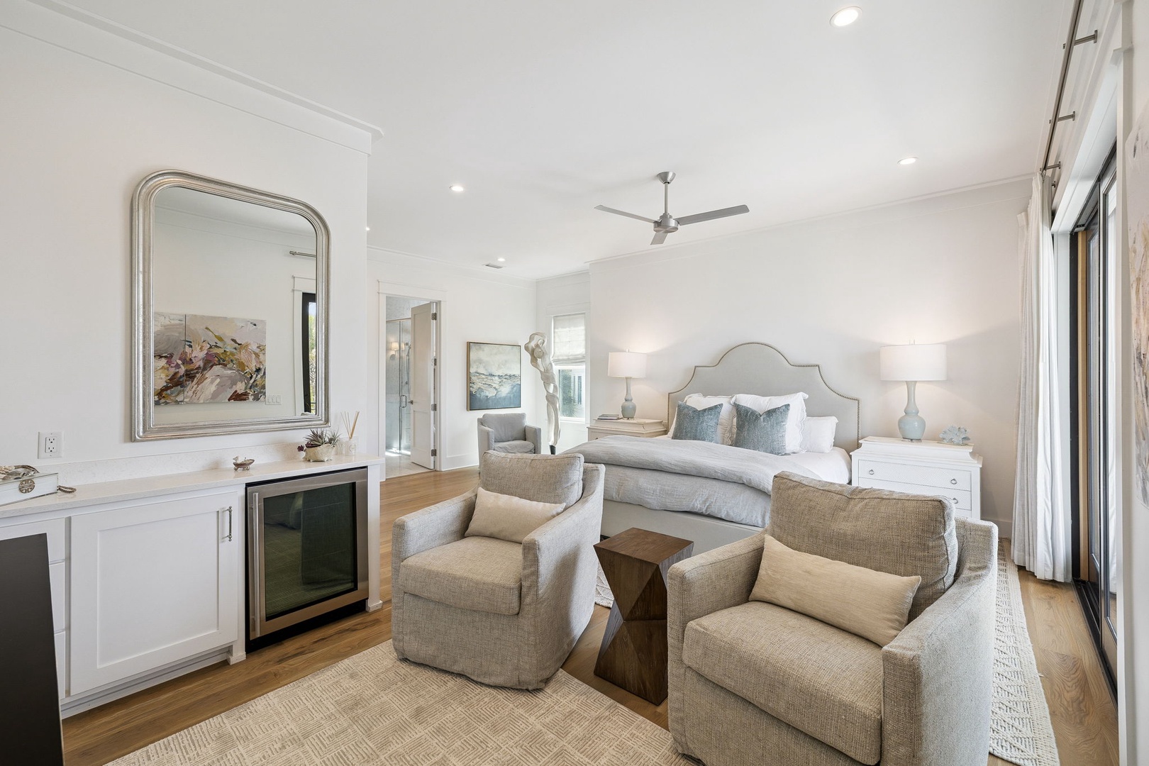 Unwind in your elegant bedroom suite with cozy seating area, fireplace, and coastal artwork creating the perfect retreat.