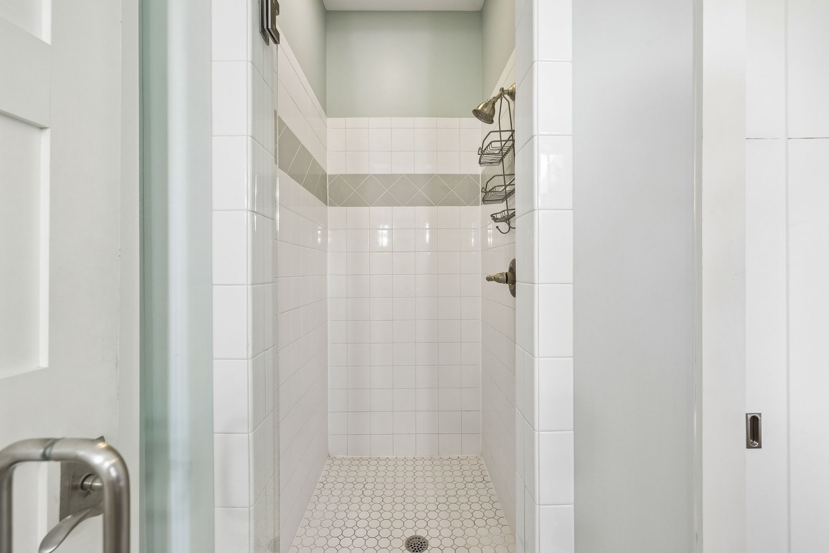 Step into your private walk-in shower with elegant white subway tile and a soothing accent stripe. Fresh and modern, it's your perfect start to the day.