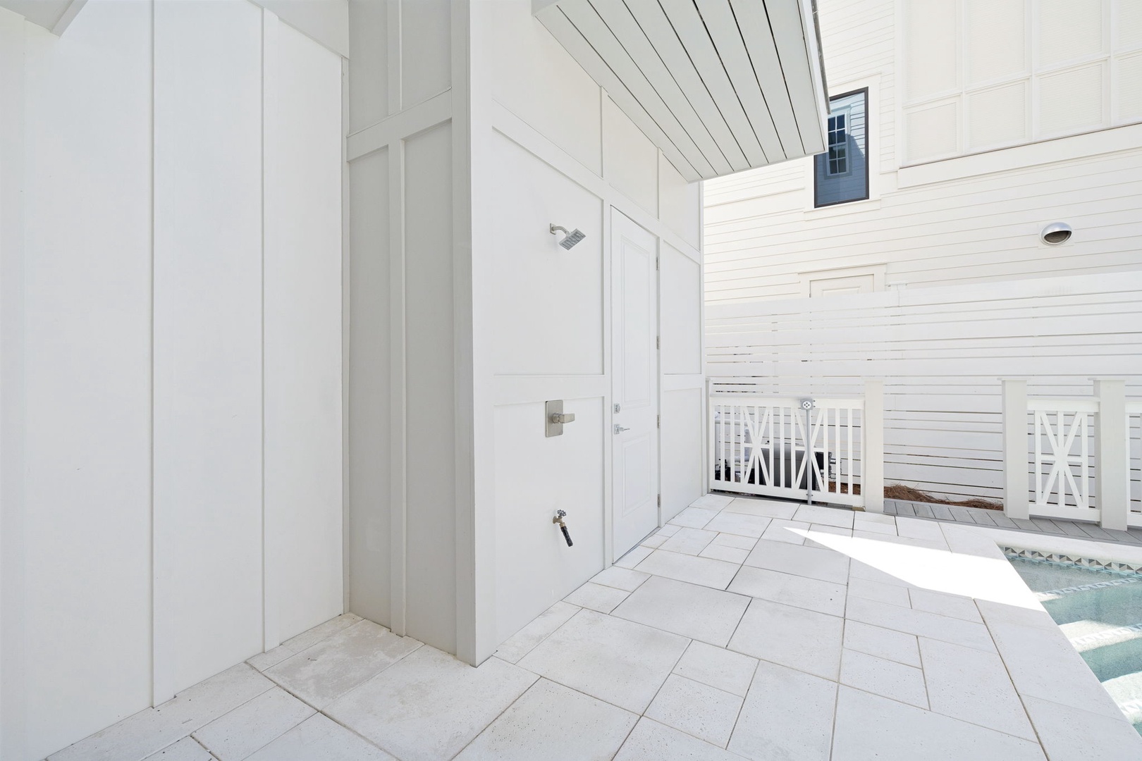 Step into your private outdoor shower oasis, where sleek white walls and stone tiles create the perfect refreshing retreat steps from the pool.
