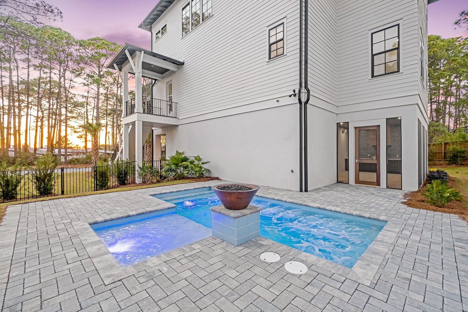 Modern coastal home featuring private pool and spa with stunning sunset views through surrounding pines.