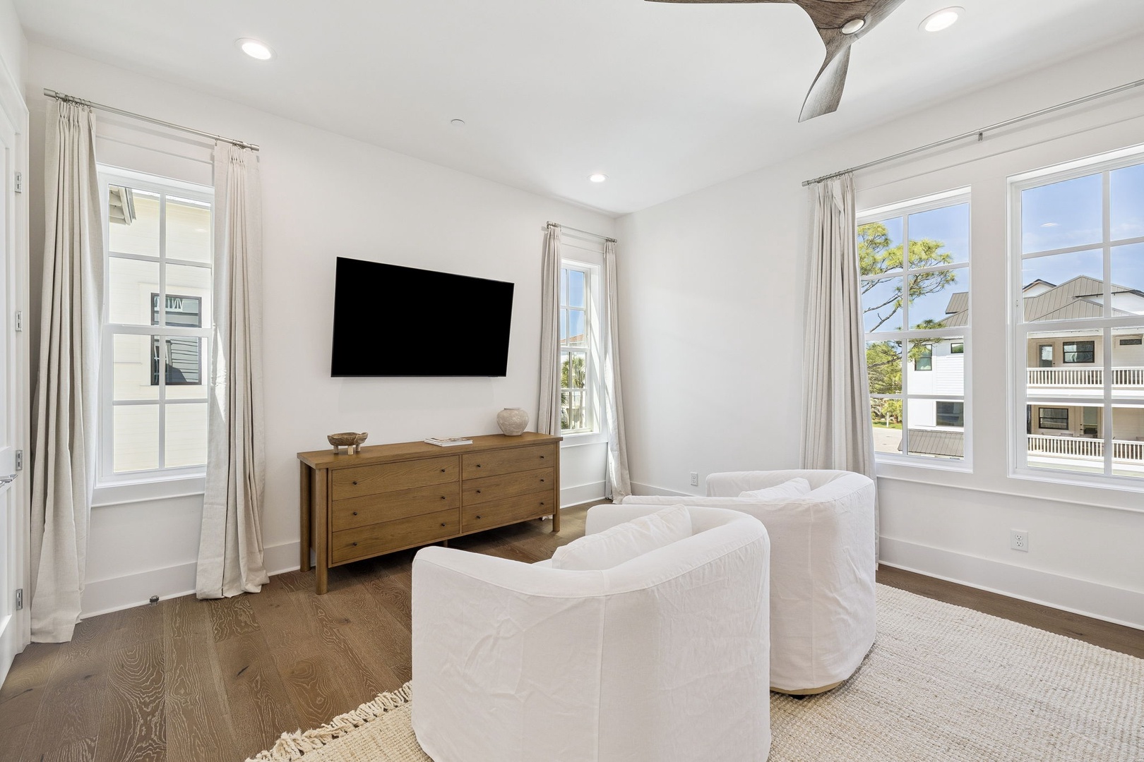 Unwind in your bright living room with cozy seating, flat-screen TV, and peaceful views from multiple windows.