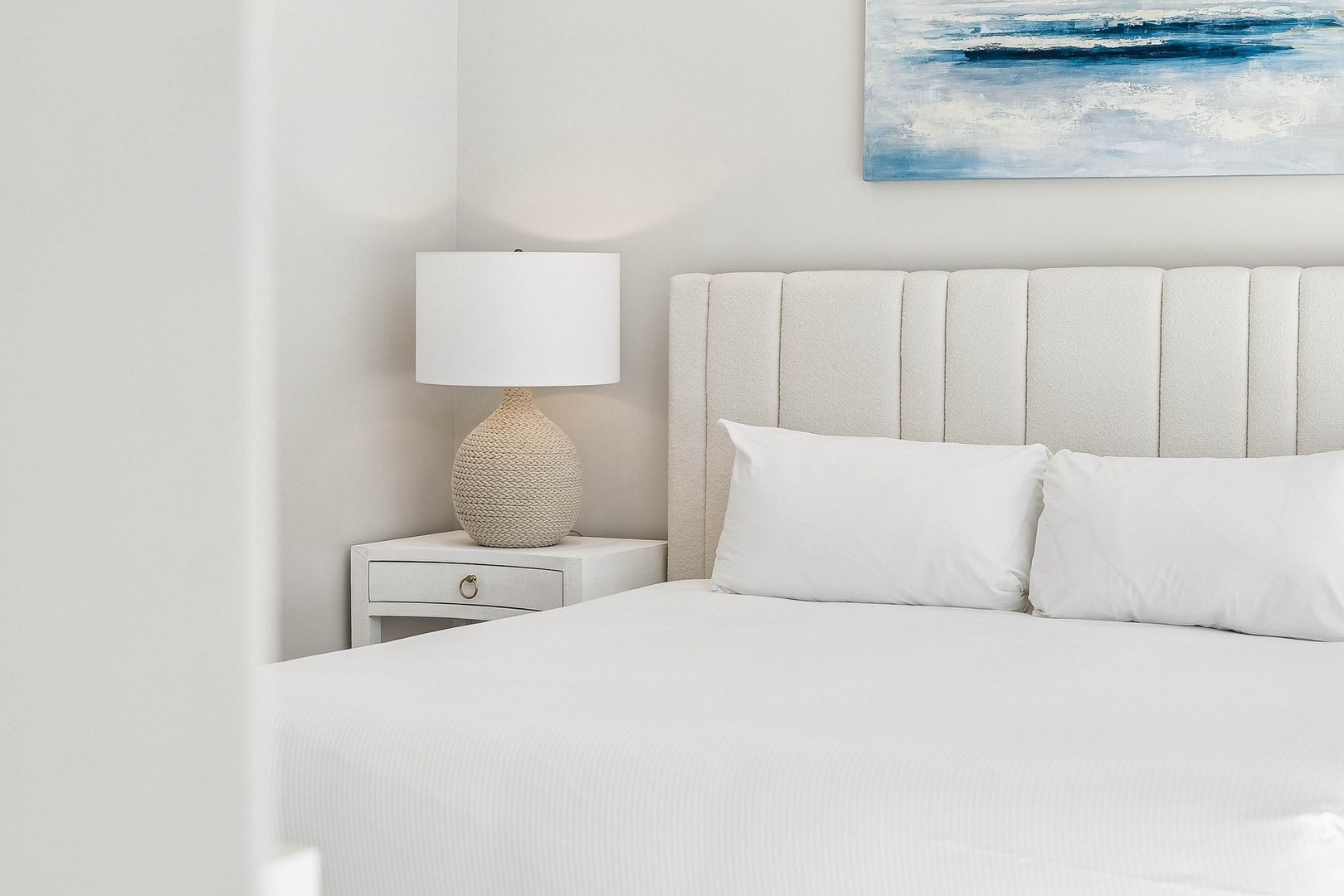 Rest easy in your coastal-inspired bedroom with plush linens and soothing artwork above your bed—perfect for peaceful mornings and serene nights.