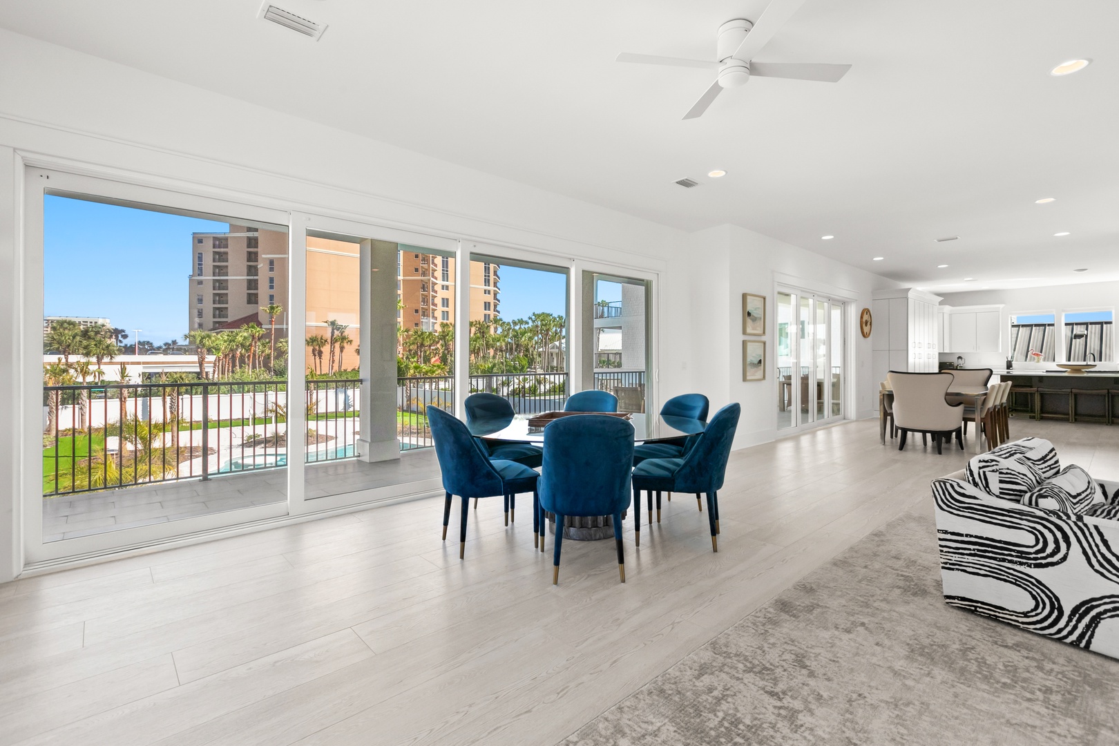 Gather around the elegant blue dining table and soak in your waterfront views through floor-to-ceiling windows. The open layout flows seamlessly into a bright, modern living space perfect for relaxing after a day of adventure.