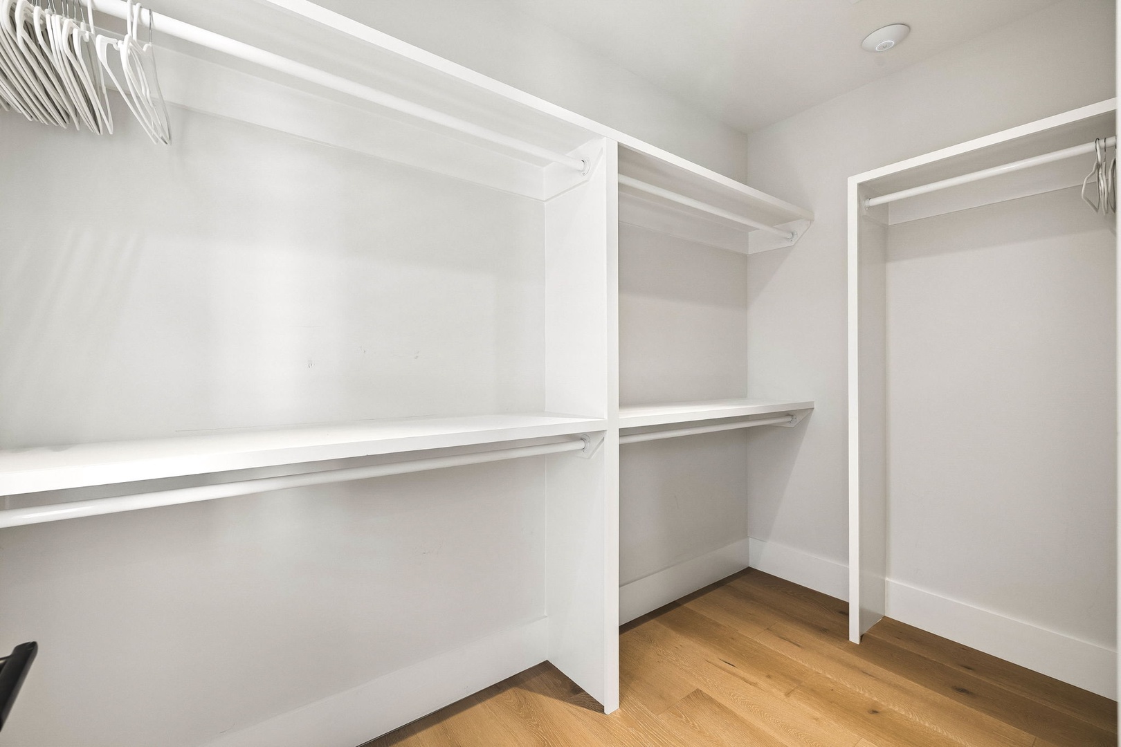 Your spacious walk-in closet features custom shelving and hanging rods, offering ample storage for all your belongings in a bright, clean space.