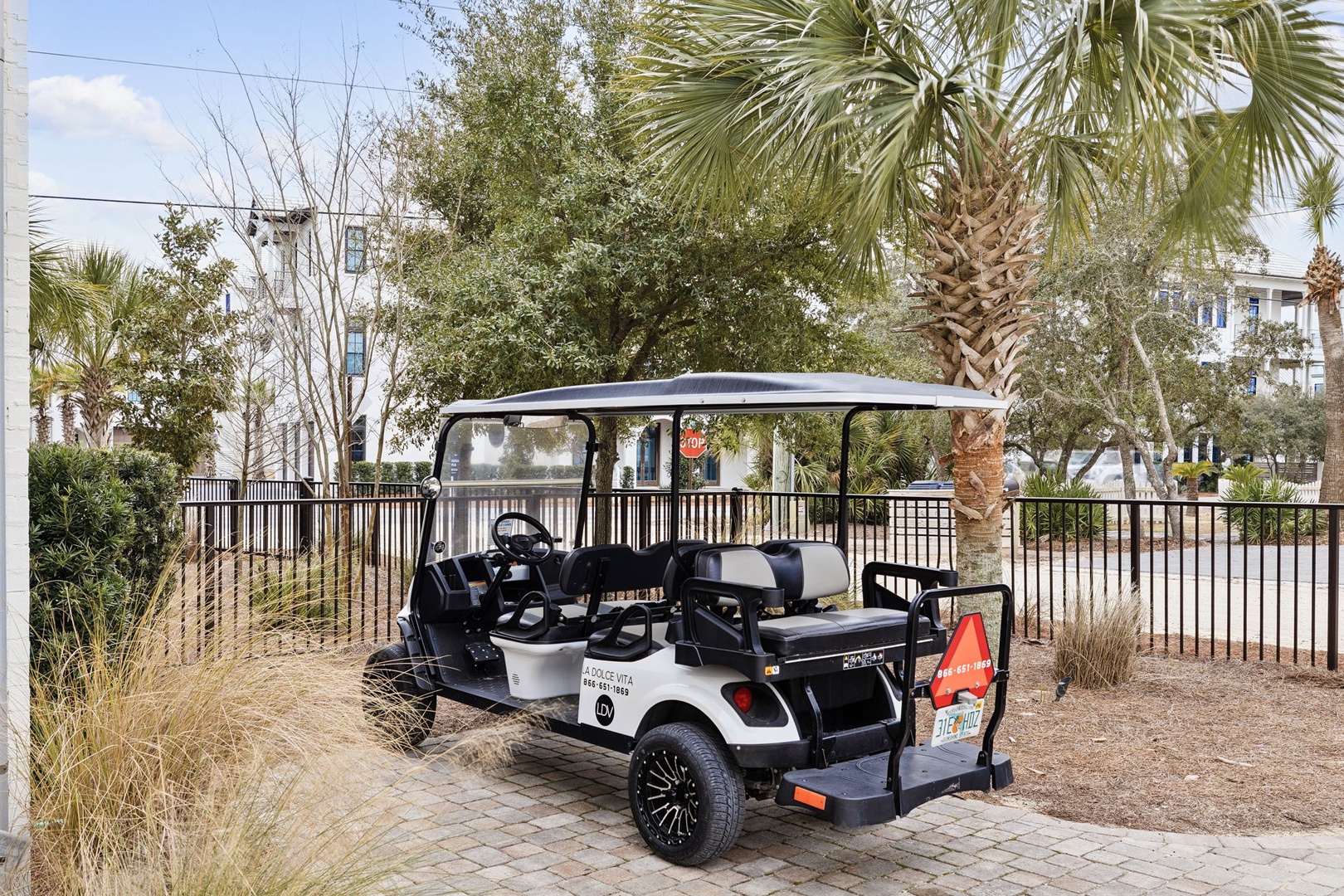 Property shuttle cart ready to transport guests through the tropical landscaped grounds surrounded by palm trees and resort buildings.