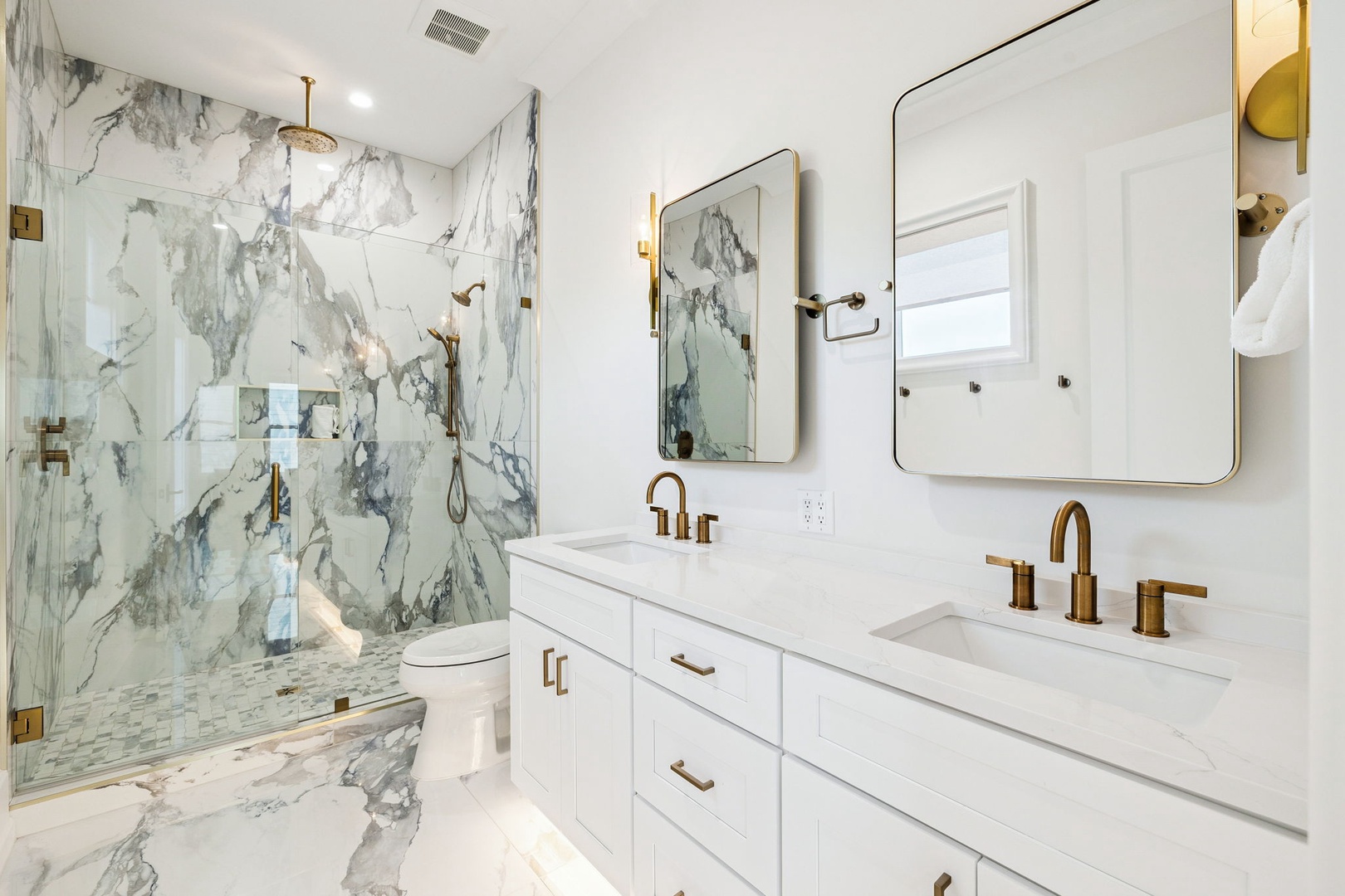 Your luxurious marble bathroom features dual vanities, rainfall shower, and elegant gold accents for spa-like relaxation.