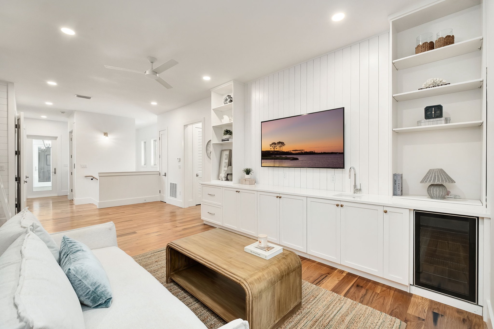 Unwind in your bright coastal living room where white built-ins and warm wood floors create the perfect space to relax after beach days.