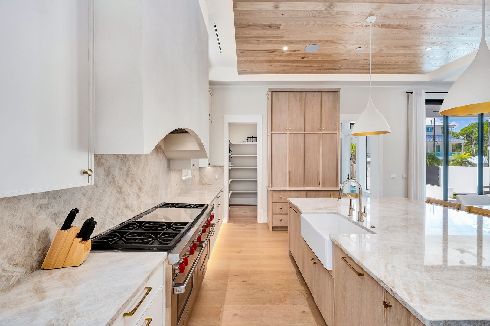 Bright, modern kitchen with marble countertops and sleek wood cabinetry. The soaring ceiling draws your eye up, while natural light floods the open layout, making meal prep a pleasure.