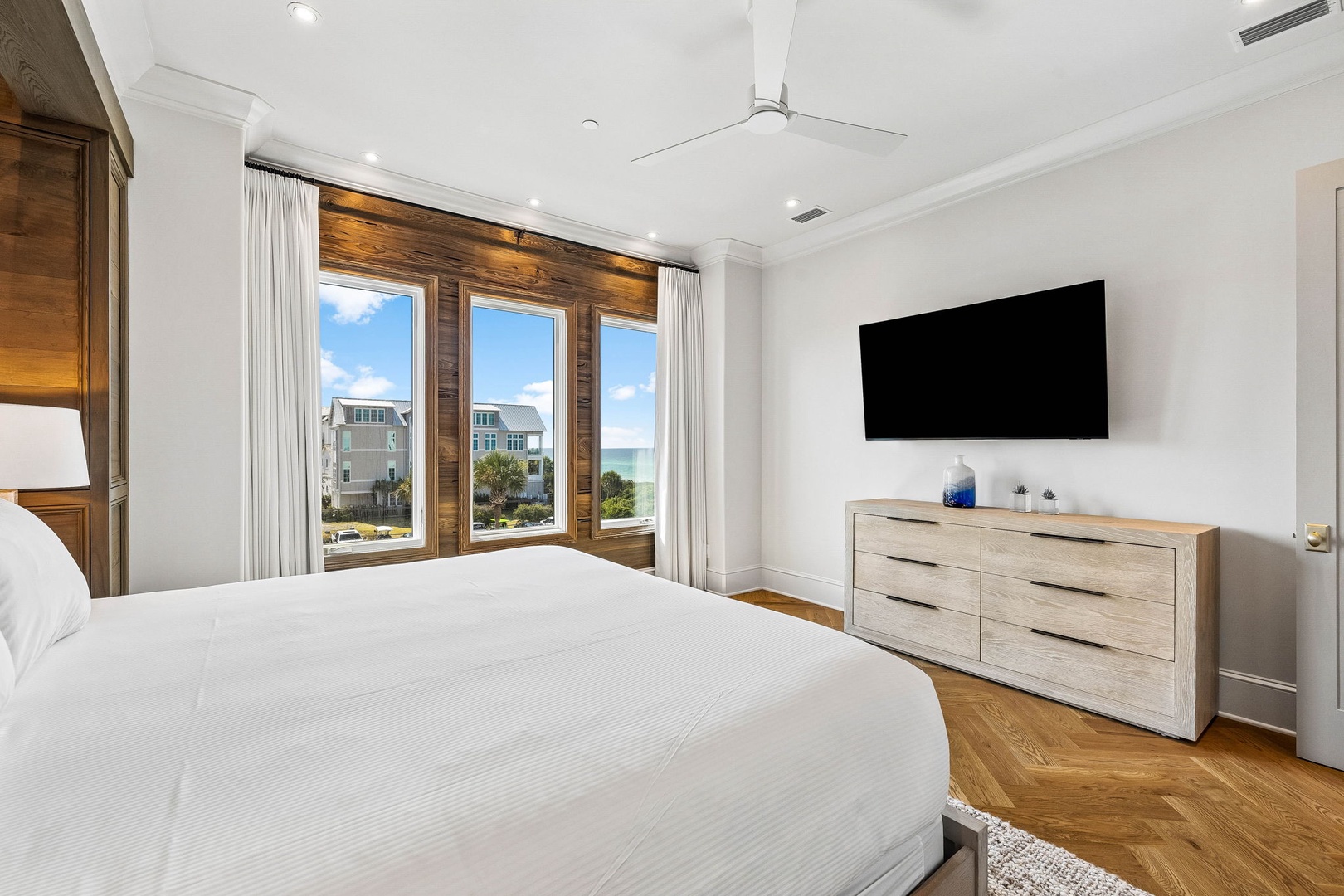 Unwind in your serene bedroom with coastal views framed by rich wood accents. Wake to beach breezes and slip into vacation mode surrounded by crisp linens and modern comfort.