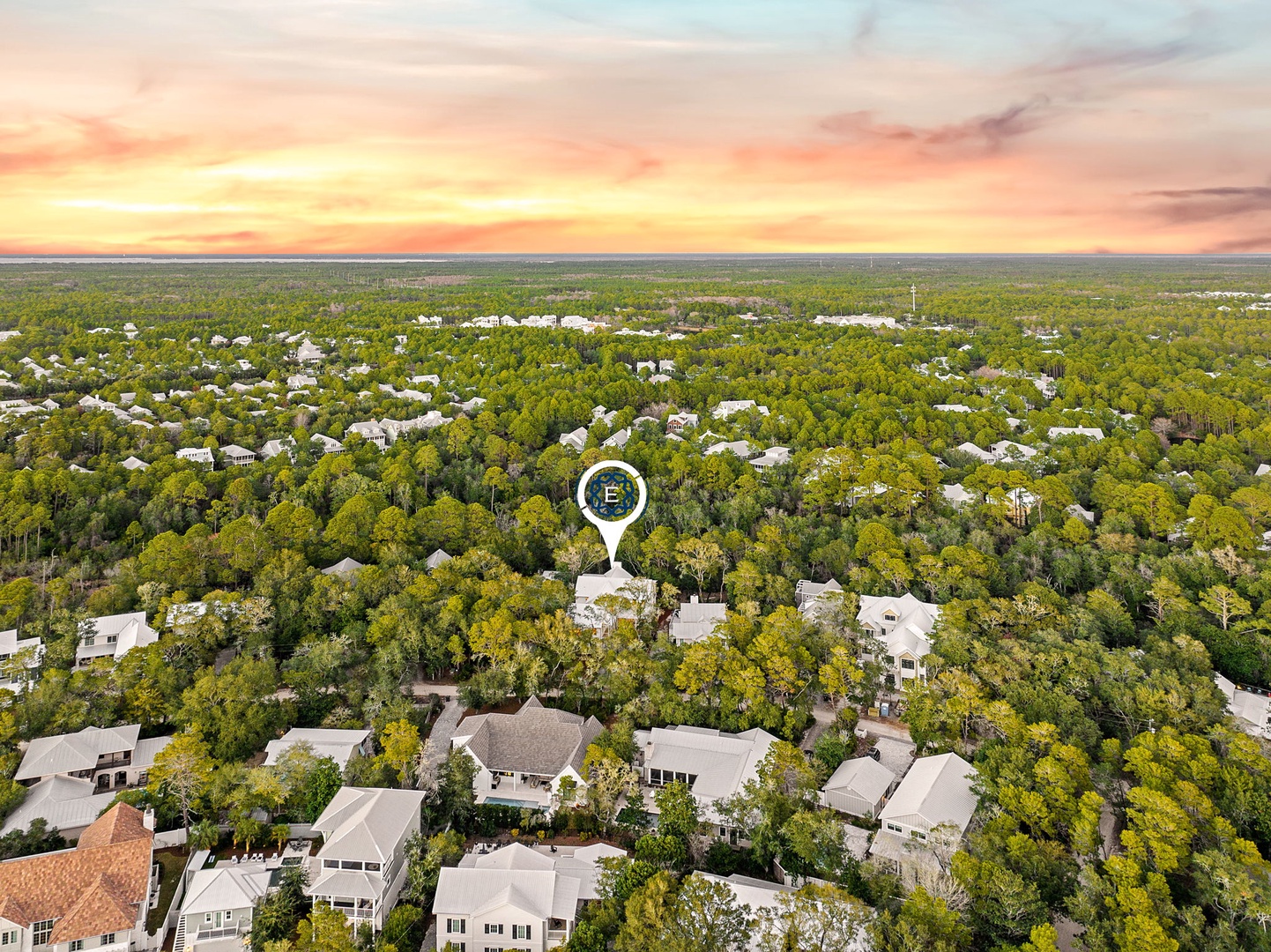 Aerial view of a tree-lined residential neighborhood at sunset, with the property marked among peaceful suburban homes.