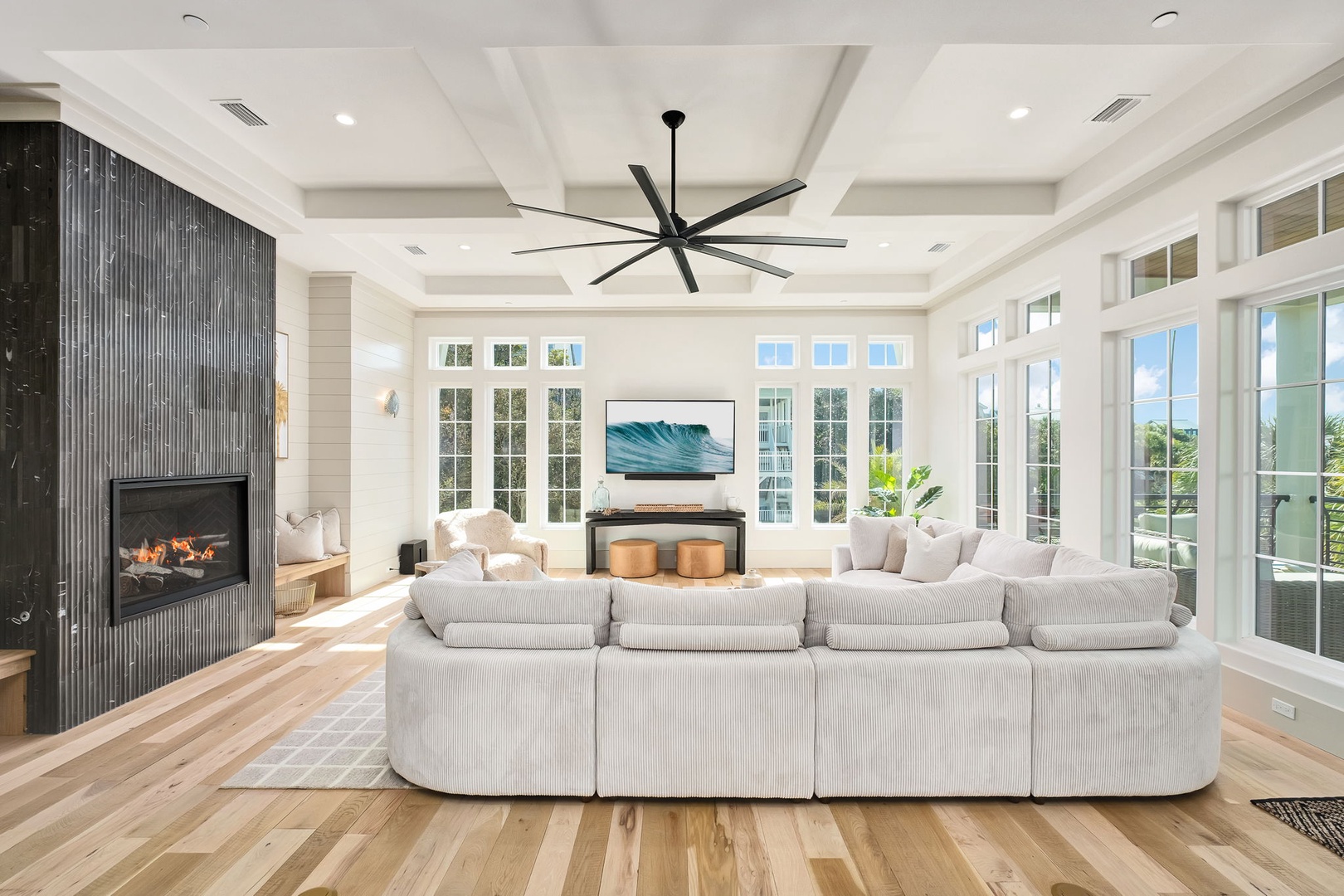 Sink into plush seating by your cozy fireplace, where natural light floods through floor-to-ceiling windows and coffered ceilings create an elegant retreat.