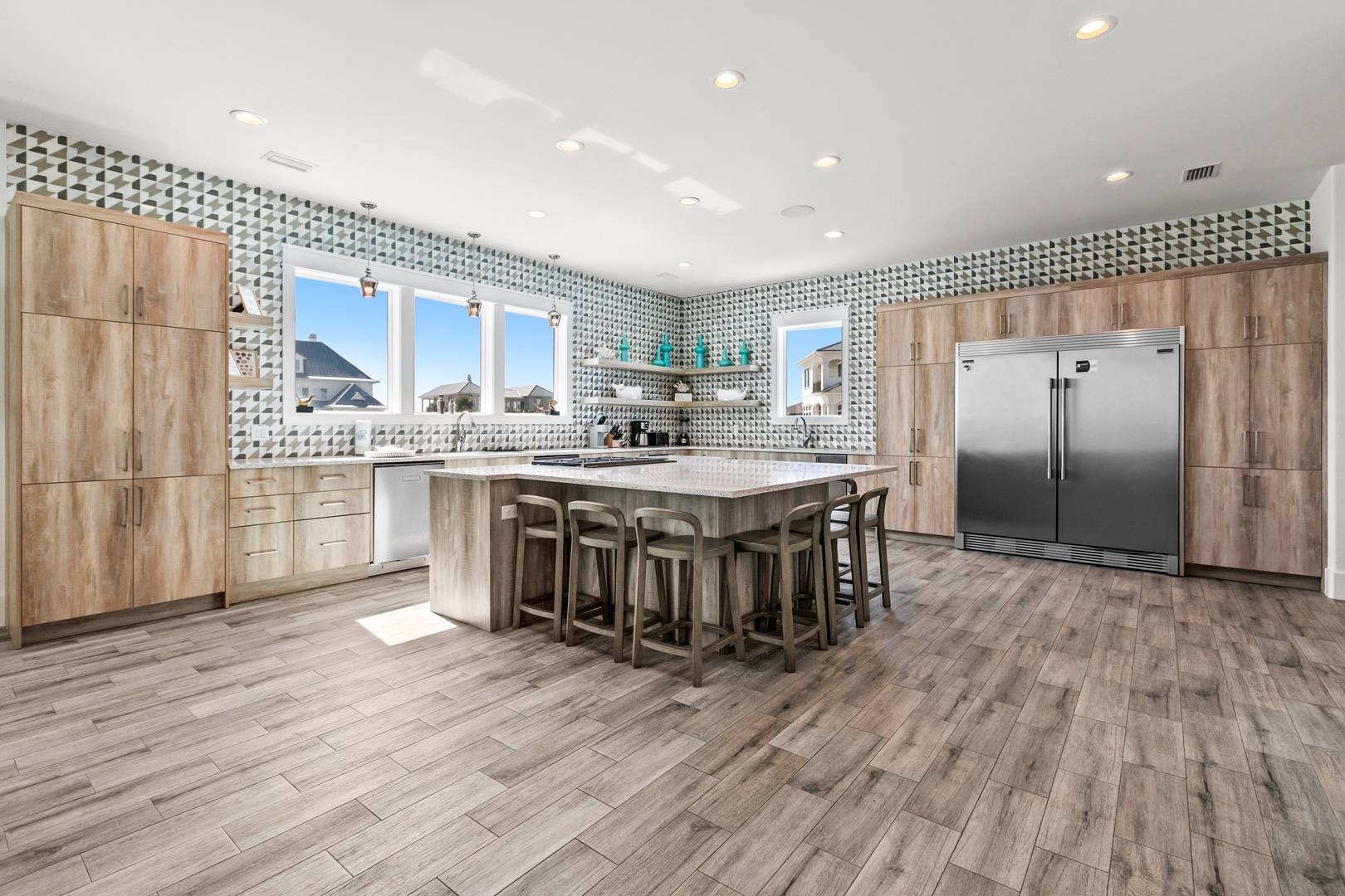 You'll love gathering around this spacious kitchen island for meals and conversation. Natural light floods the modern space, highlighting sleek appliances and warm wood tones that make this the perfect place to cook and connect.