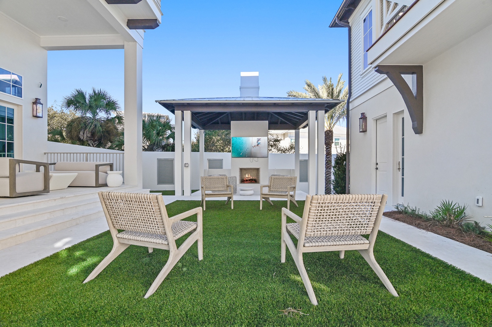 Relax in your private courtyard oasis with inviting seating, a cozy outdoor fireplace, and lush tropical landscaping creating your perfect retreat under sunny skies.