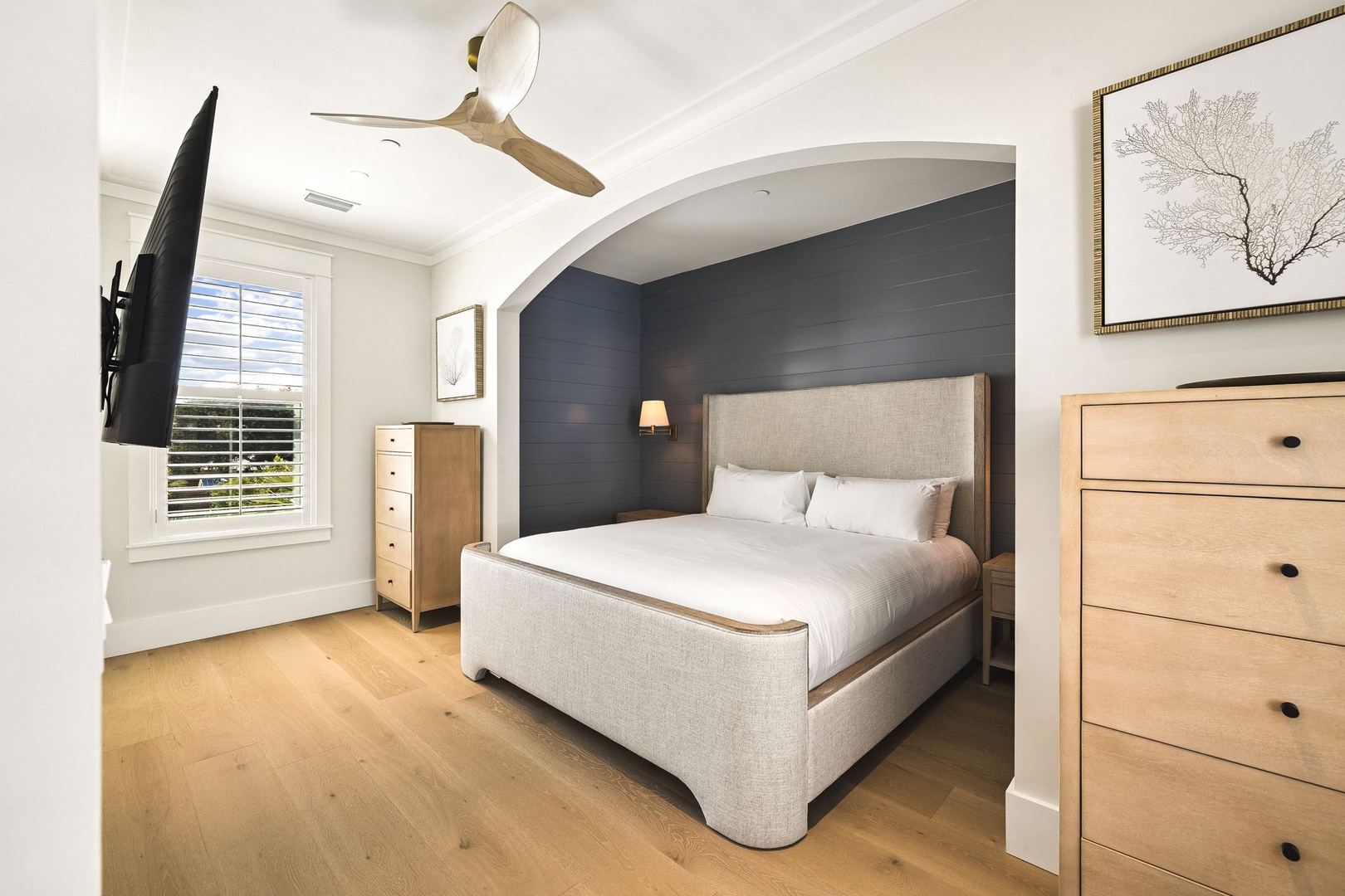 Drift off in your elegant bedroom, where crisp linens, a soothing accent wall, and a gentle ceiling fan promise restful nights after exploring the area.