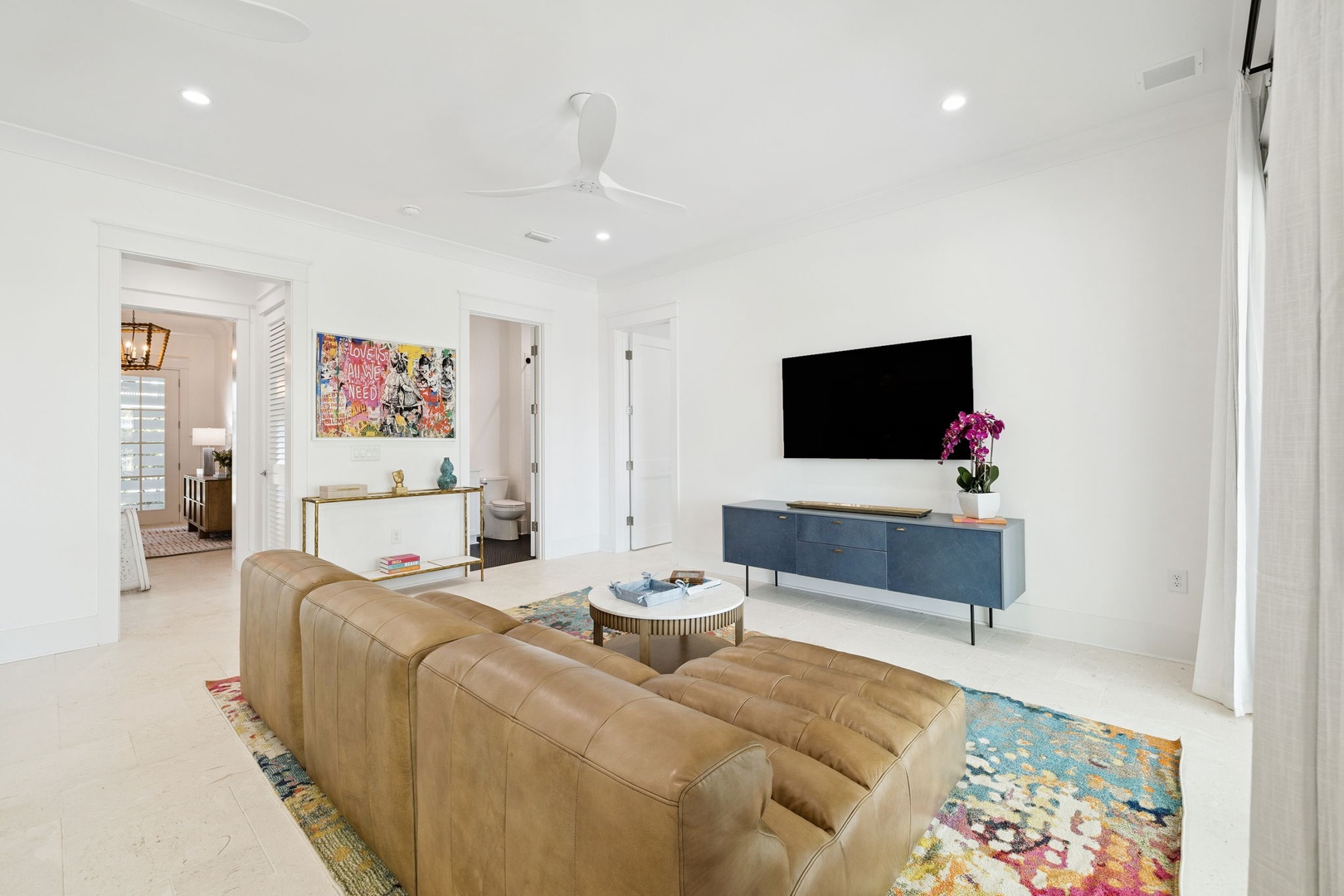 Relax in your stylish living room with plush leather seating, vibrant artwork, and modern amenities for the perfect evening unwind.