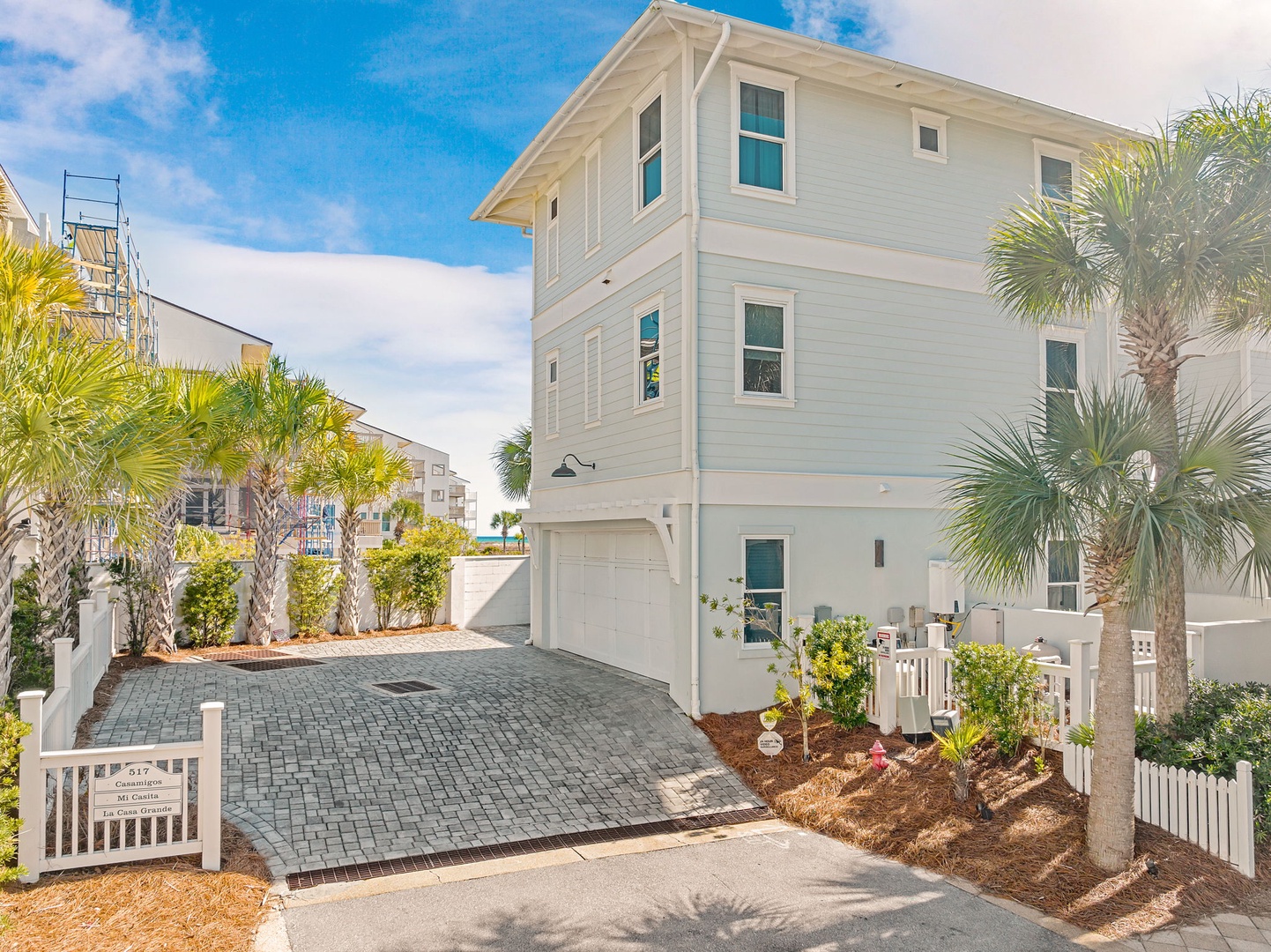 A bright coastal retreat featuring palm-lined landscaping and modern three-story architecture, positioned in a quiet beach neighborhood with convenient parking access.