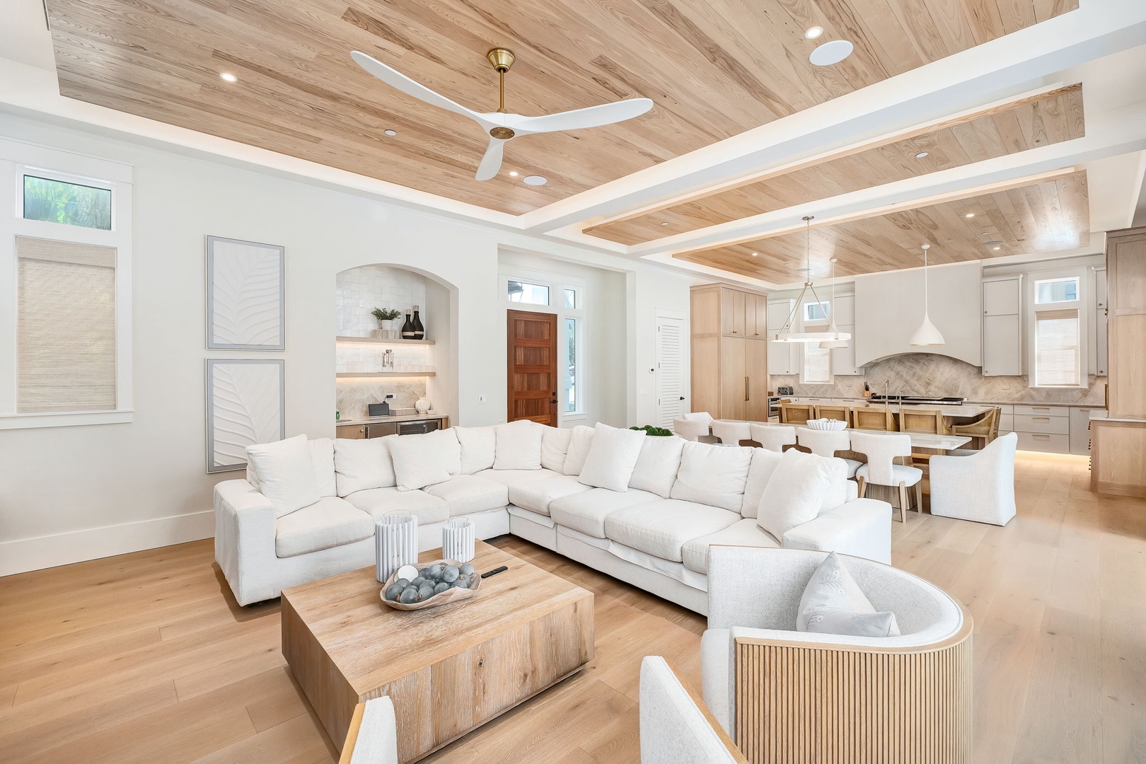 Sink into the plush sectional and let the warmth of the wood-beamed ceiling and natural light wrap around you in this bright, open-concept living space.