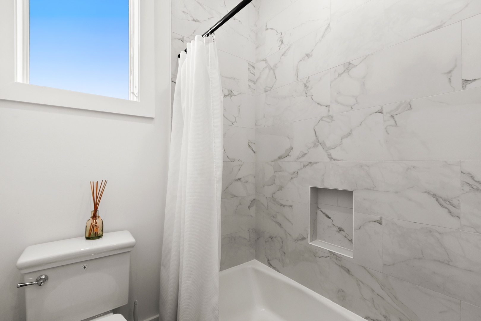 Step into your serene bathroom retreat, where elegant marble-look walls and natural light create a spa-like atmosphere perfect for unwinding after a day of adventure.